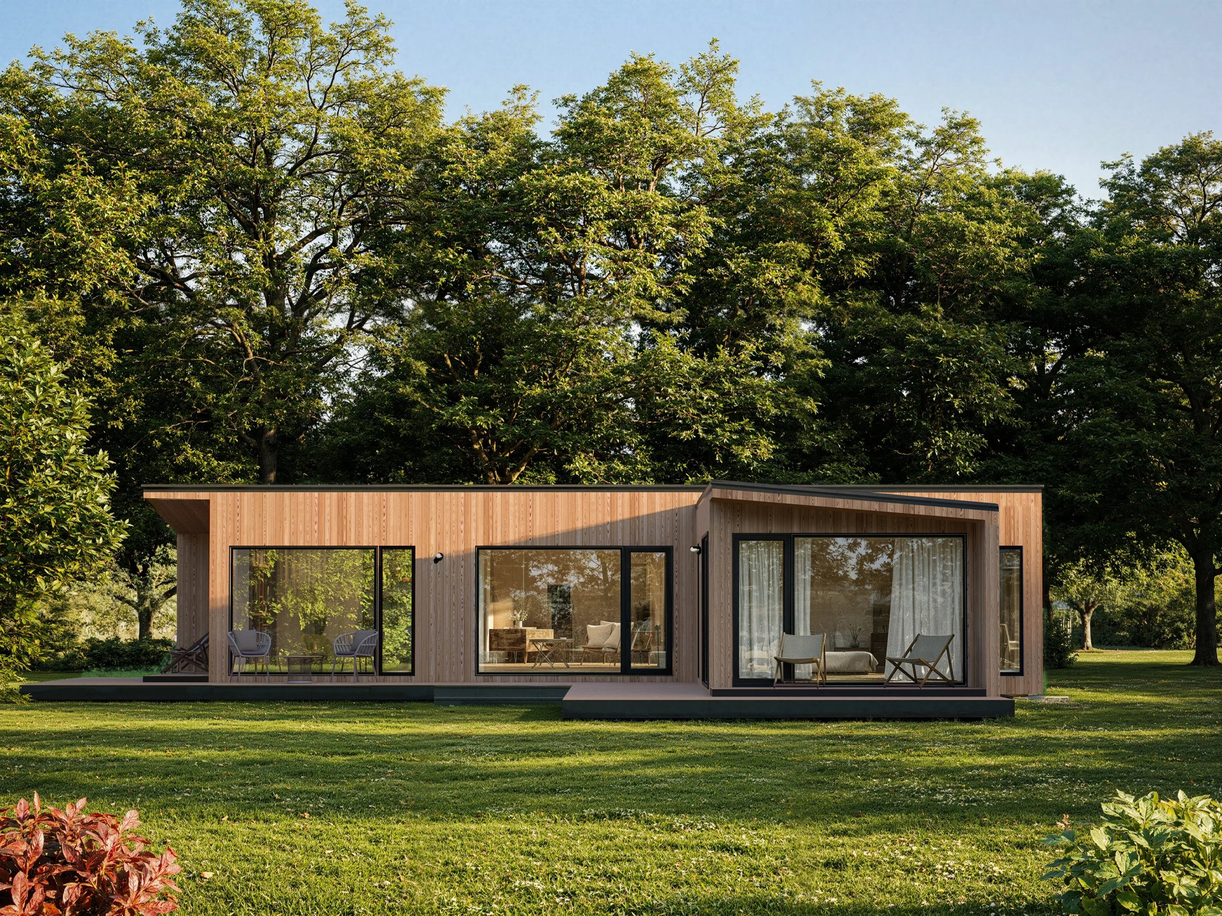 Modern wooden house with large glass windows, situated on a grassy lawn with trees in the background.