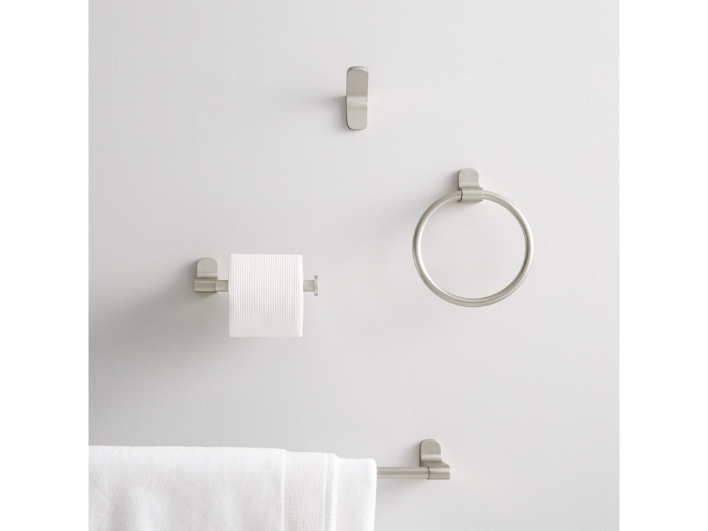 White wall with metal bathroom fixtures, including a towel ring, towel bar with a towel, a toilet paper holder with a roll, and a small hook.