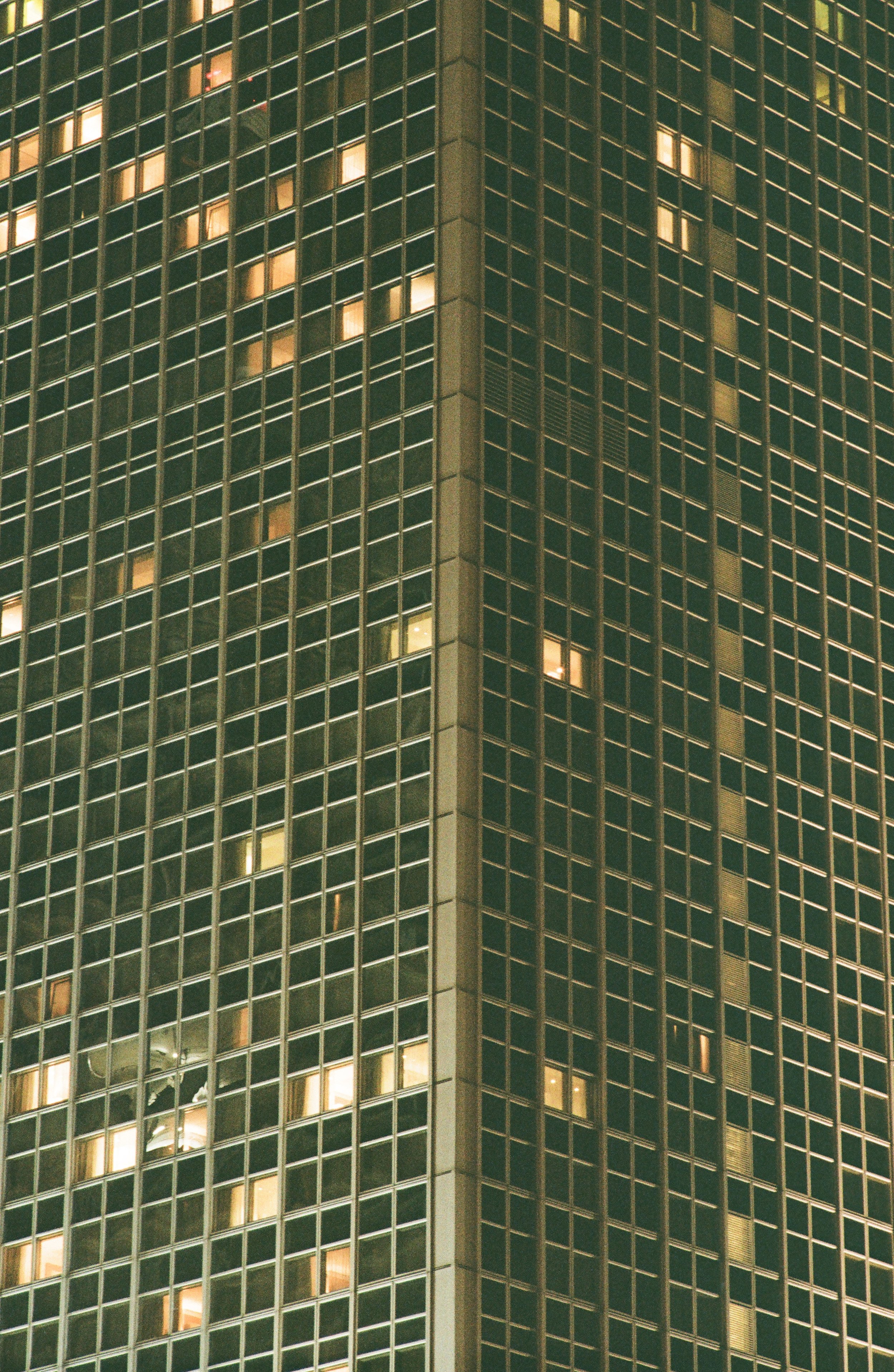 Nahaufnahme eines modernen Wolkenkratzers mit beleuchteten Fenstern bei Nacht.