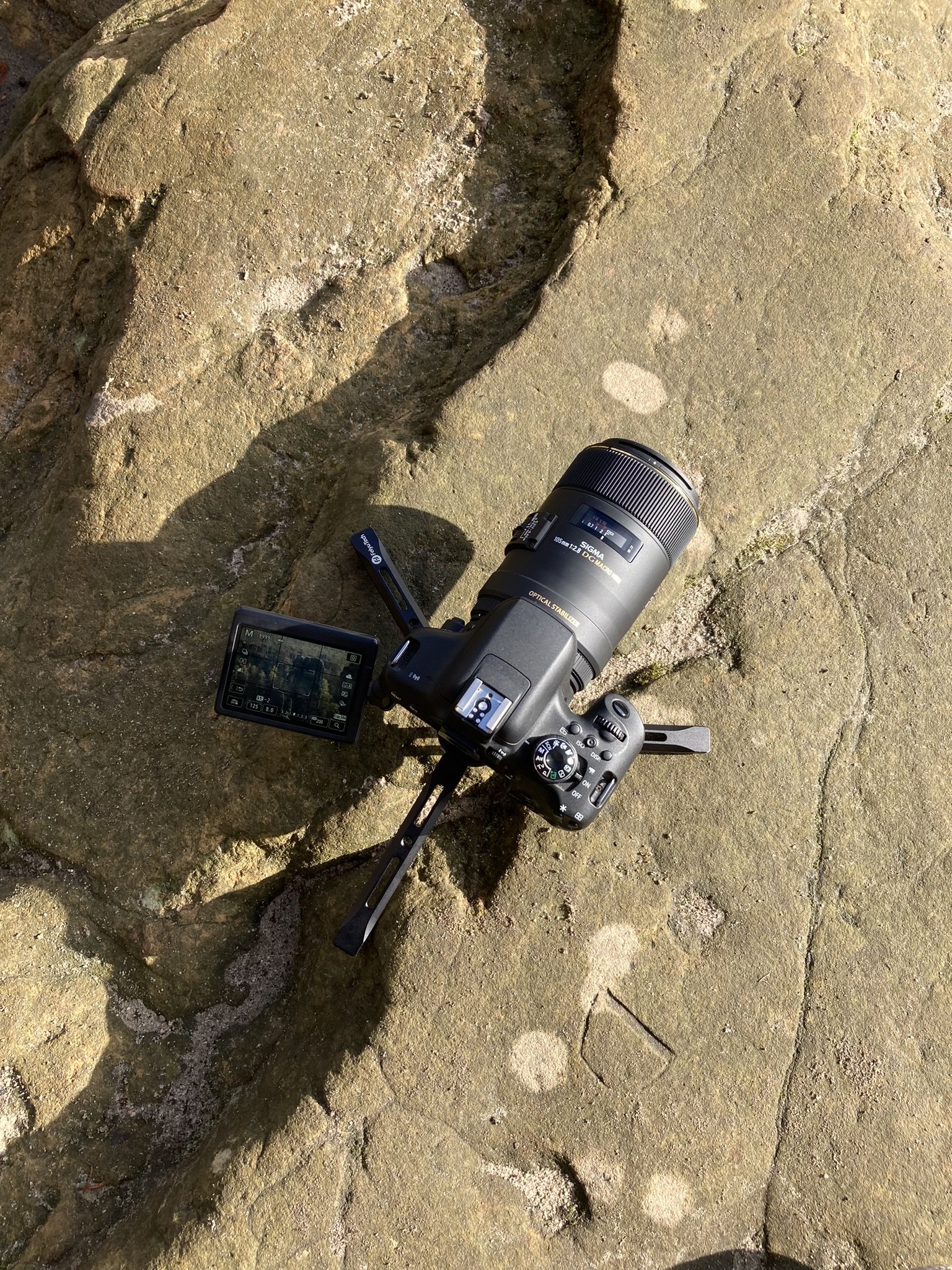 Digitale Kamera liegt auf einer steinernen Oberfläche im Freien, aufgenommen bei Sonnenlicht.
