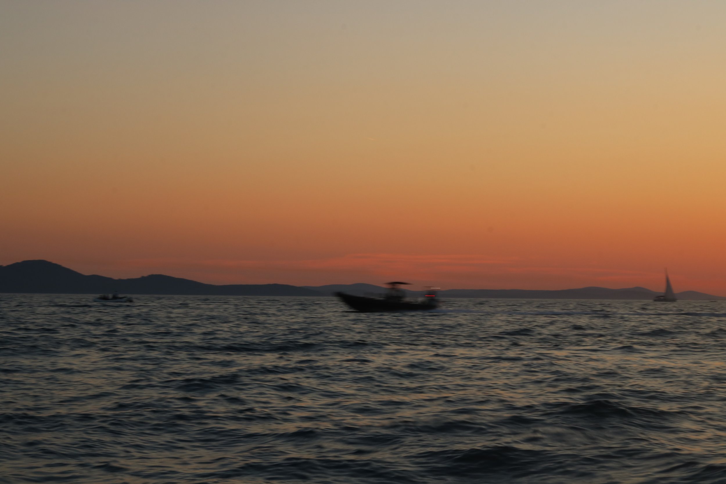 Segelboot und Boote auf dem Wasser bei Sonnenuntergang