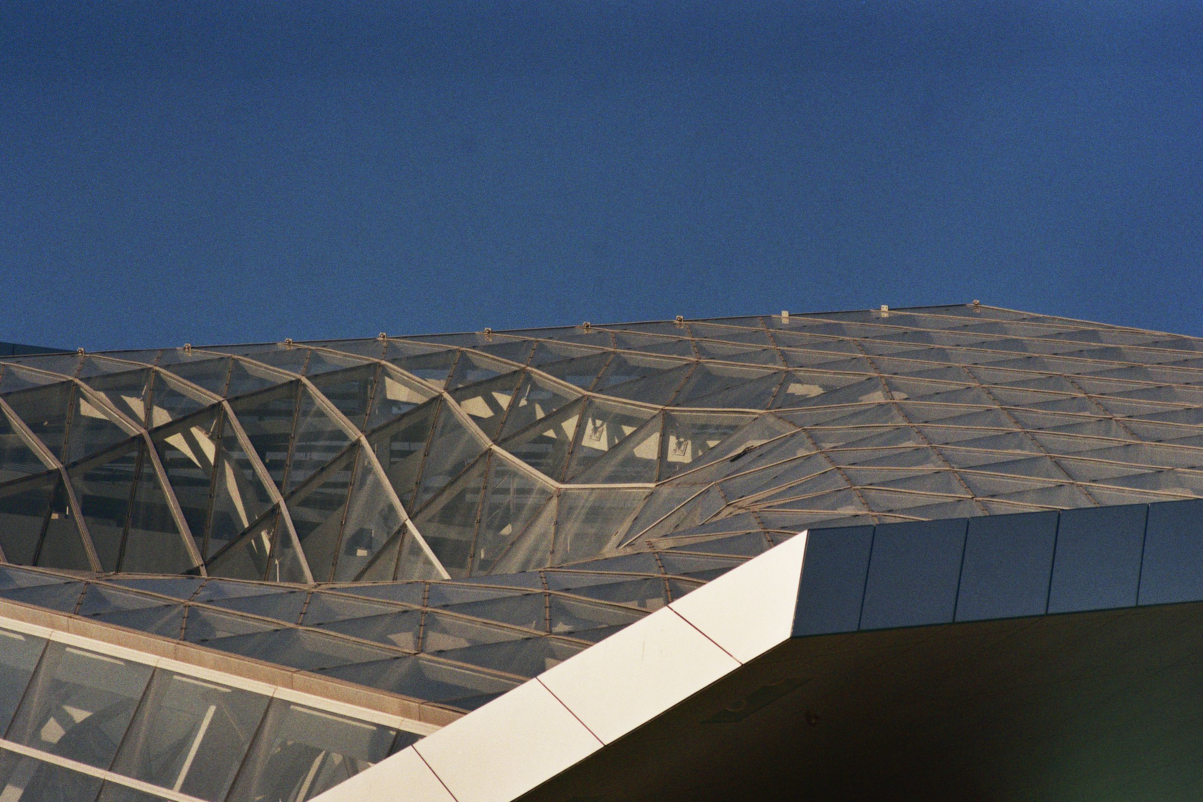 Modernes Gebäude mit geometrischem Glasdach gegen blauen Himmel