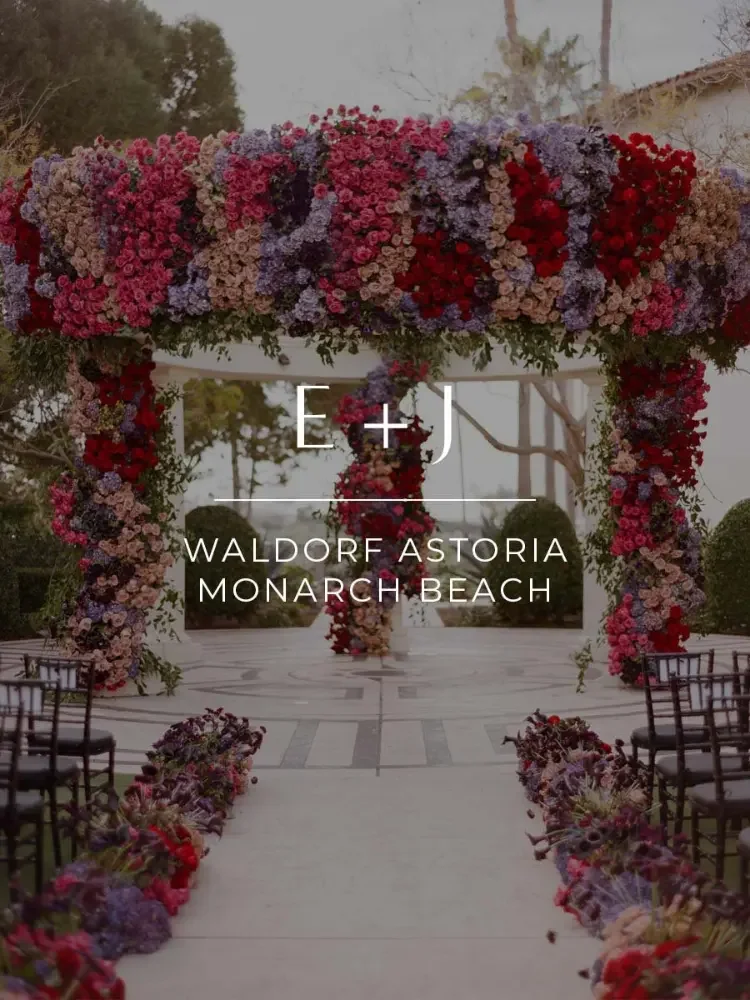 A flower arch adorned with red, pink, purple, and white flowers at Waldorf Astoria Monarch Beach for a wedding ceremony.