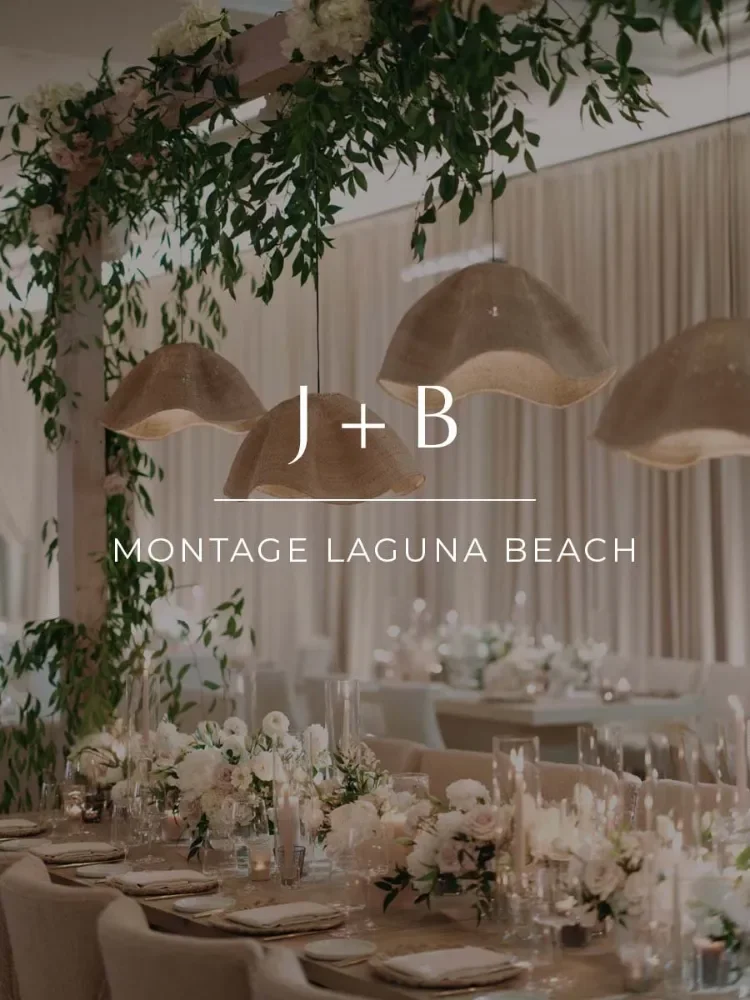 Elegant wedding reception table with floral arrangements, candles, and hanging pendant lights, decorated in soft neutral tones.