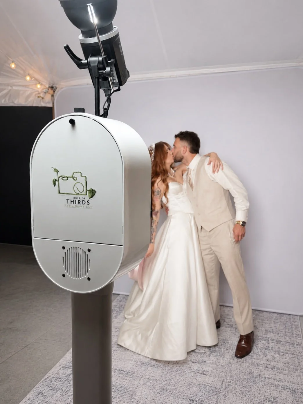 Bride and groom celebrating with guests in a modern photo booth.