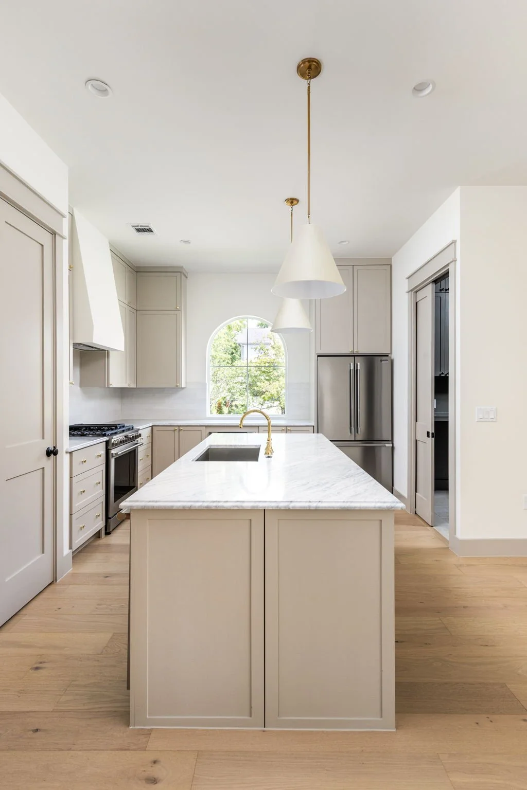 Modern kitchen with white cabinets, a marble island, stainless steel appliances, and pendant lights.