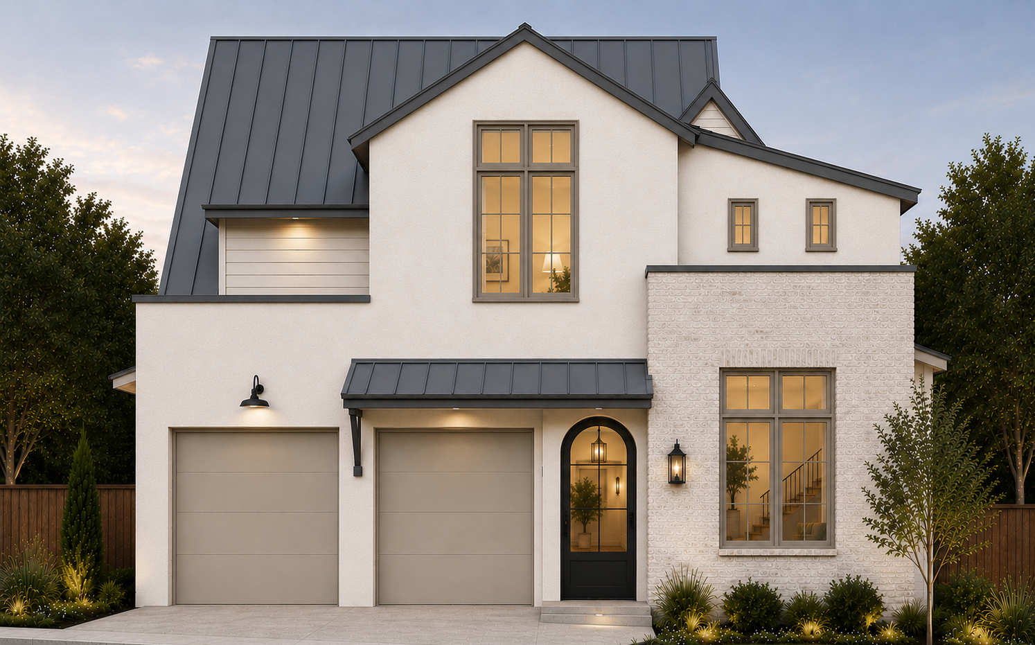 Modern two-story house with beige stucco and white brick exterior, dark gray metal roof, and large windows, illuminated from inside at dusk.