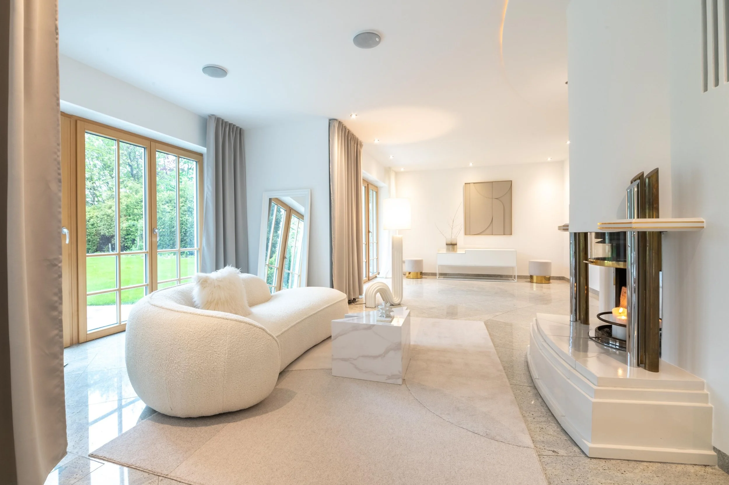 Luxus homestaging in Villa in München mit einem runden Sofa in beige an offenen Kamin stehend