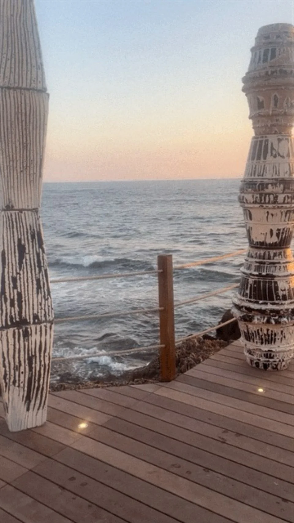 Ein Blick auf das Meer während des Sonnenuntergangs, der Holzterrasse mit bemalten Flaschen im Vordergrund