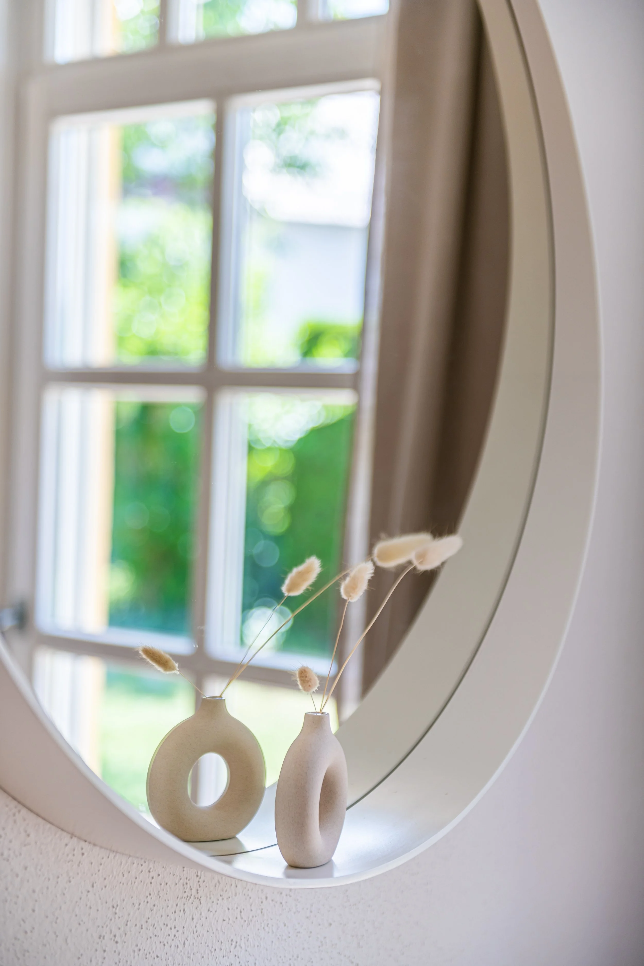 runder Spiegel in dem sich Deko spiegelt