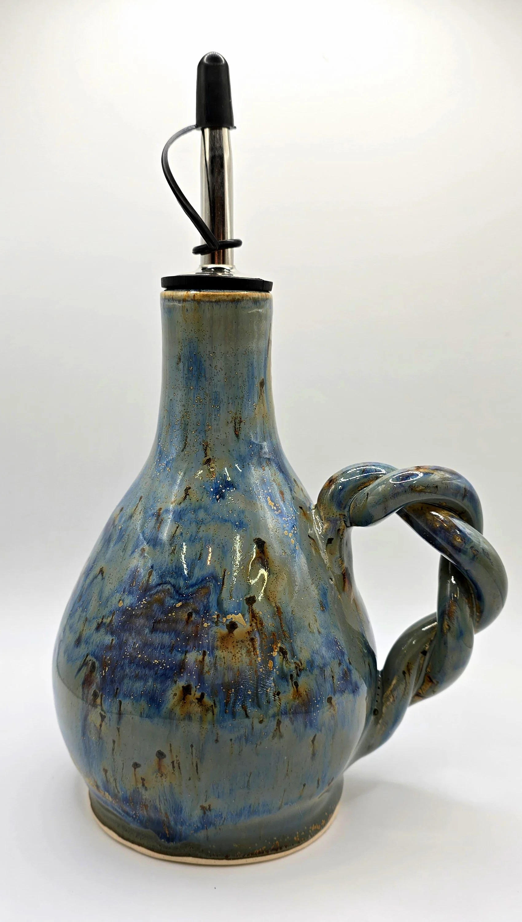 A ceramic oil cruet with a glossy glaze in blue, gray, and brown tones, featuring a twisted handle, topped with a metal pump dispenser.