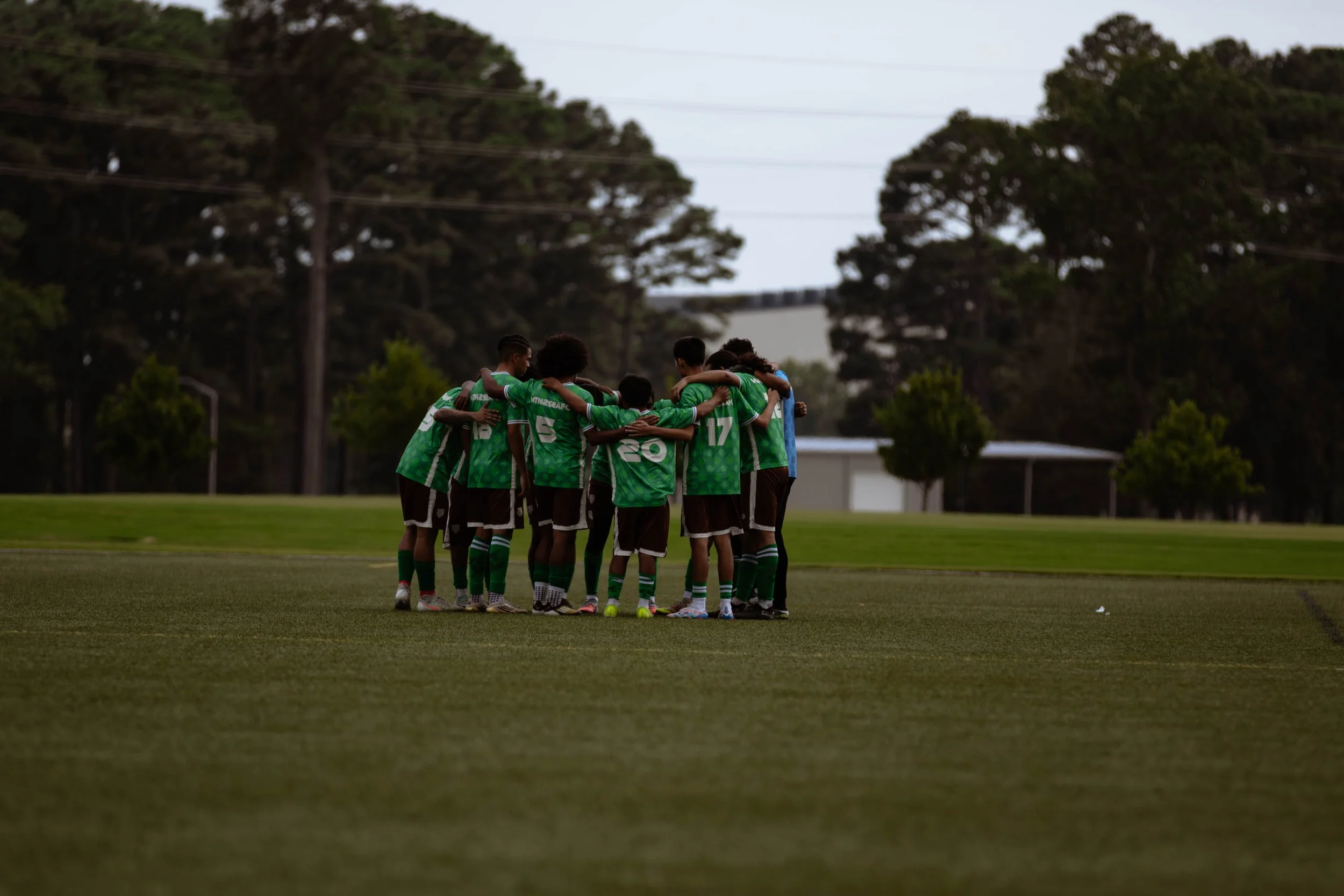 Soccer team huddled together on a field