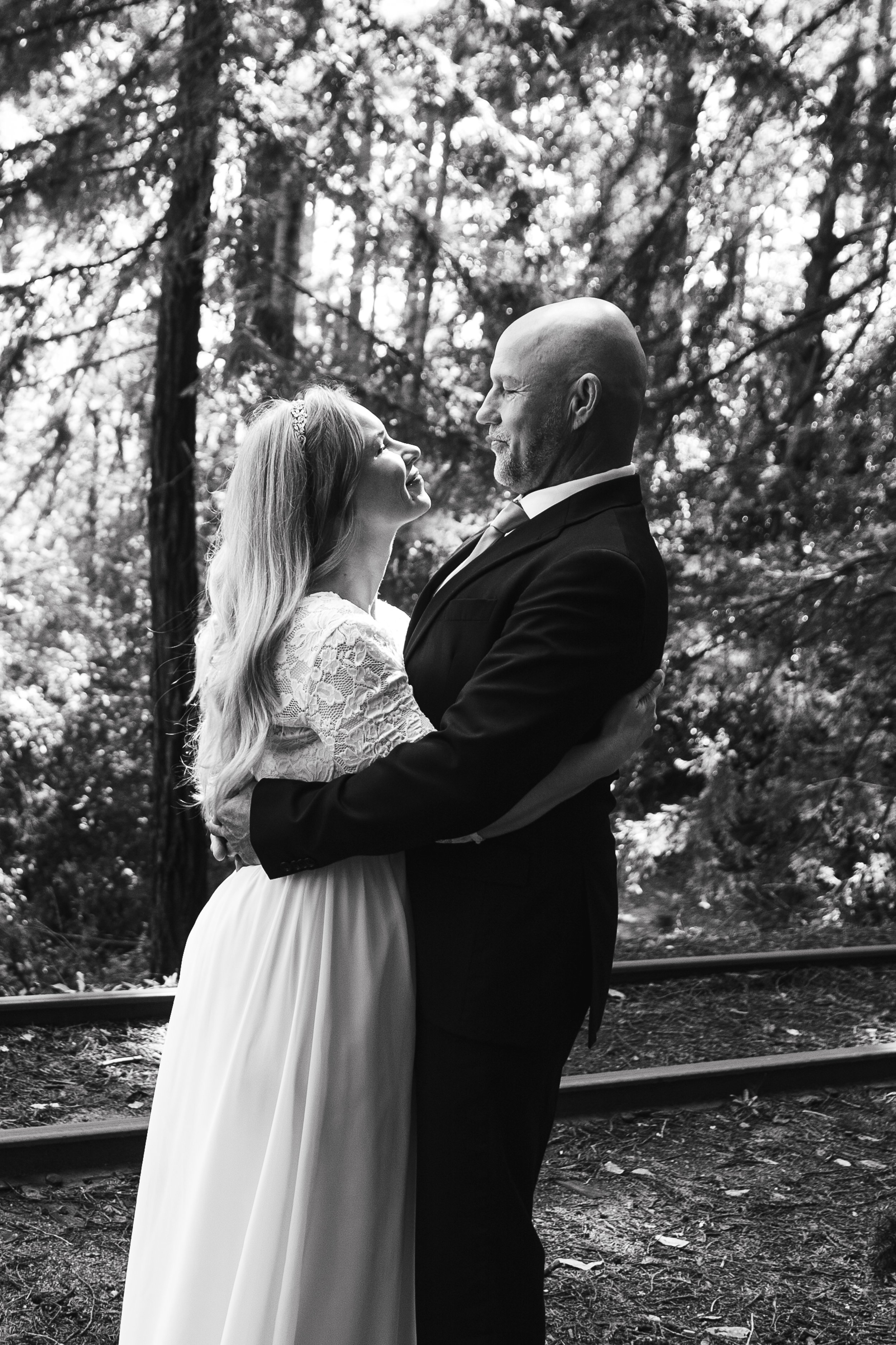 Bride and groom embracing in forest, black and white photo