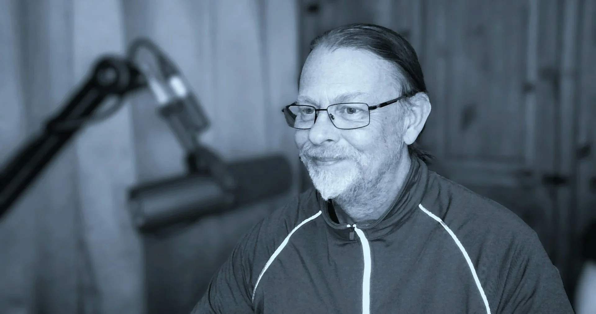 A man with gray hair, glasses, and a beard is working in the studio setting.