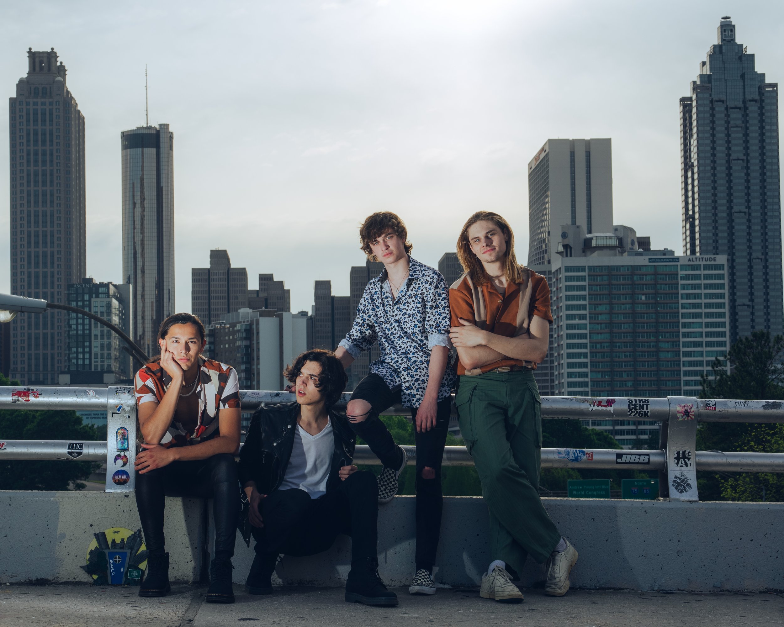 Group of young adults posing on a city bridge with tall skyscrapers in the background