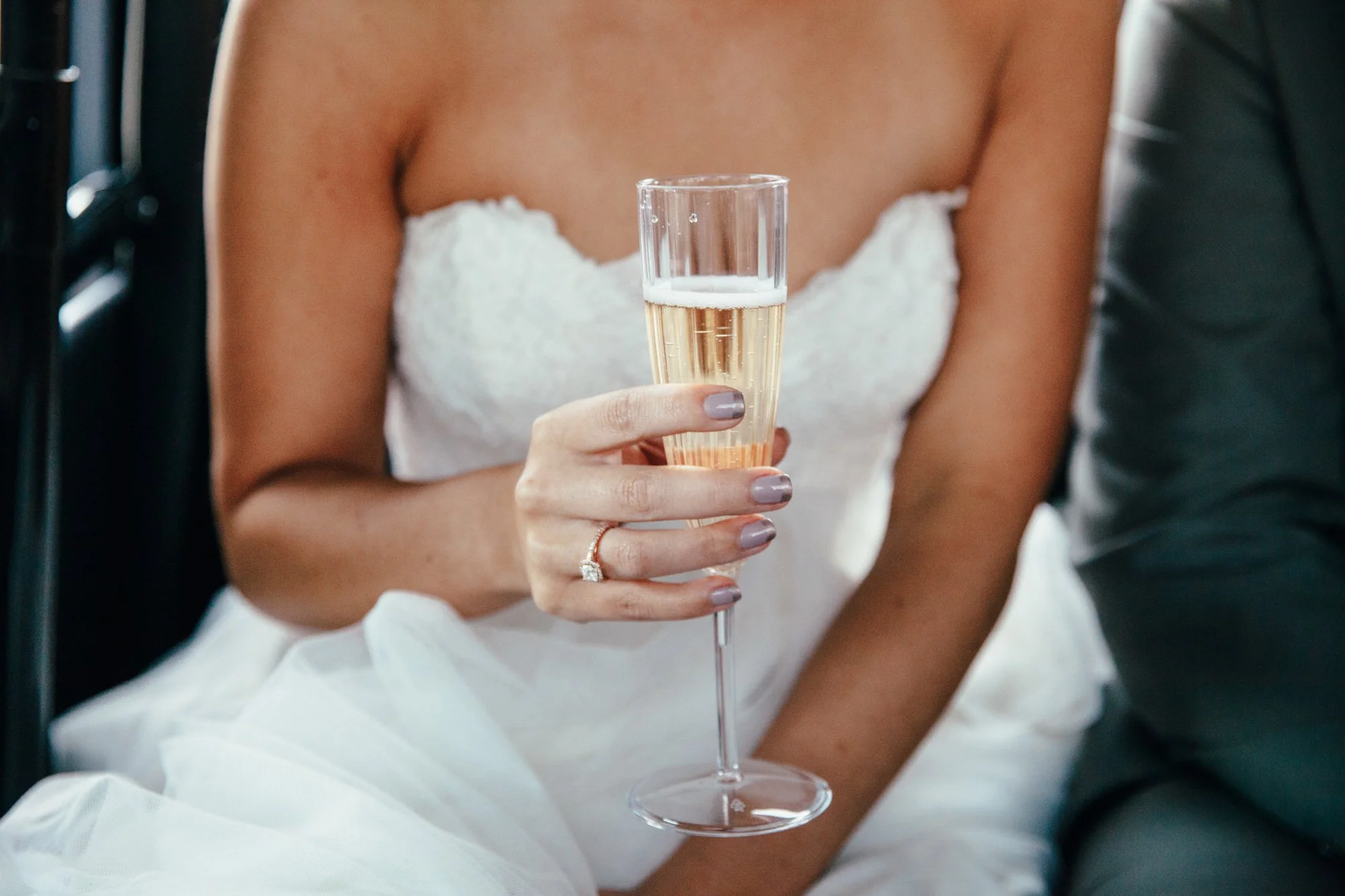 Bride holding a champagne glass, wearing a wedding dress.