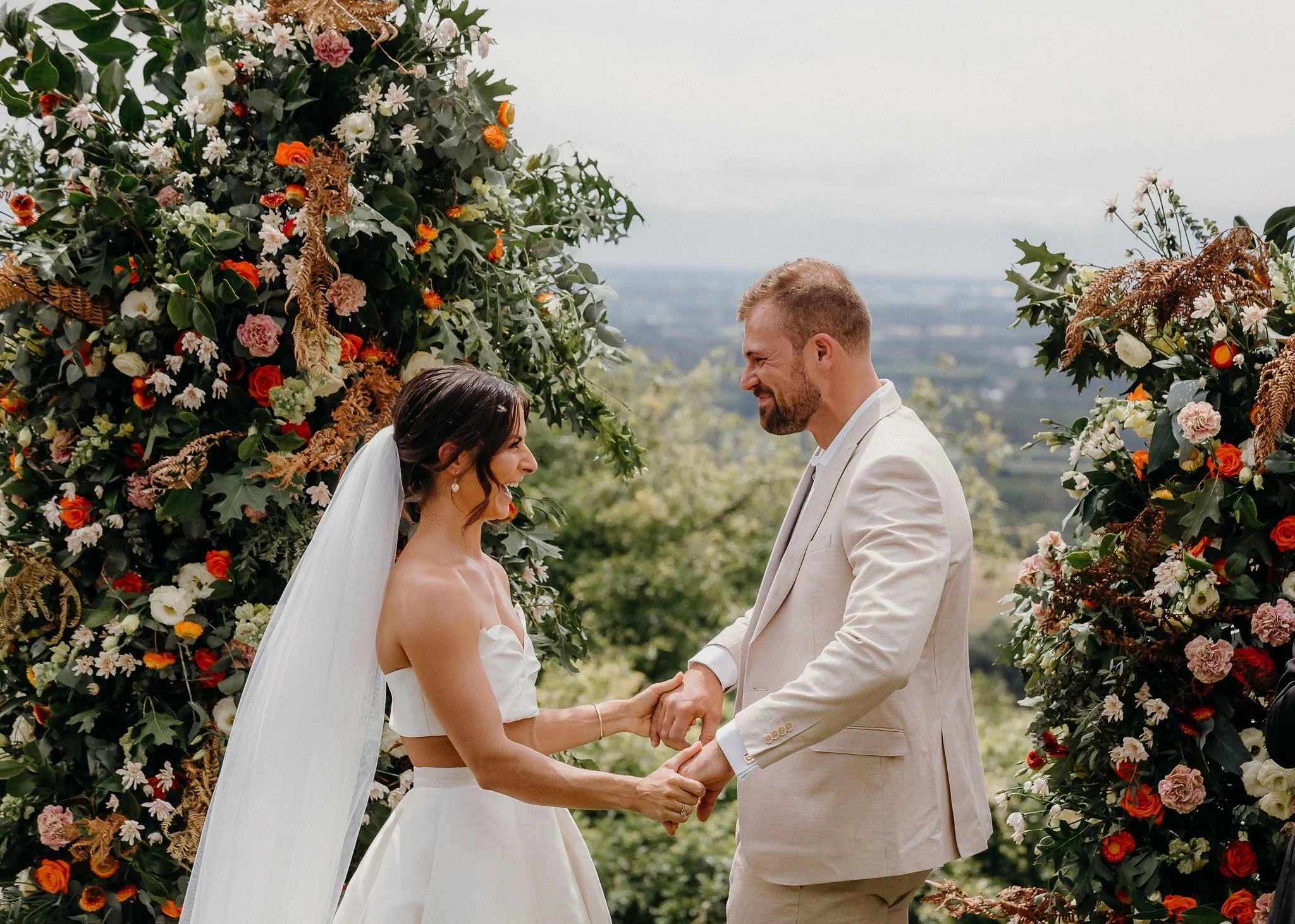 Bride and groom holding hands during their outdoor wedding ceremony at Waipuna Estate with scenic Canterbury views