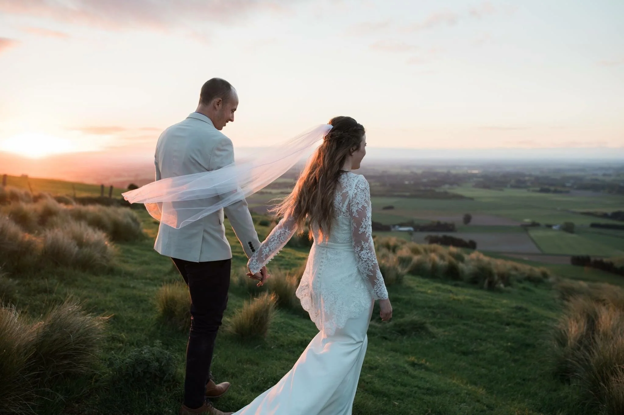 Bride and groom walking together through the scenic grounds of Waipuna Estate