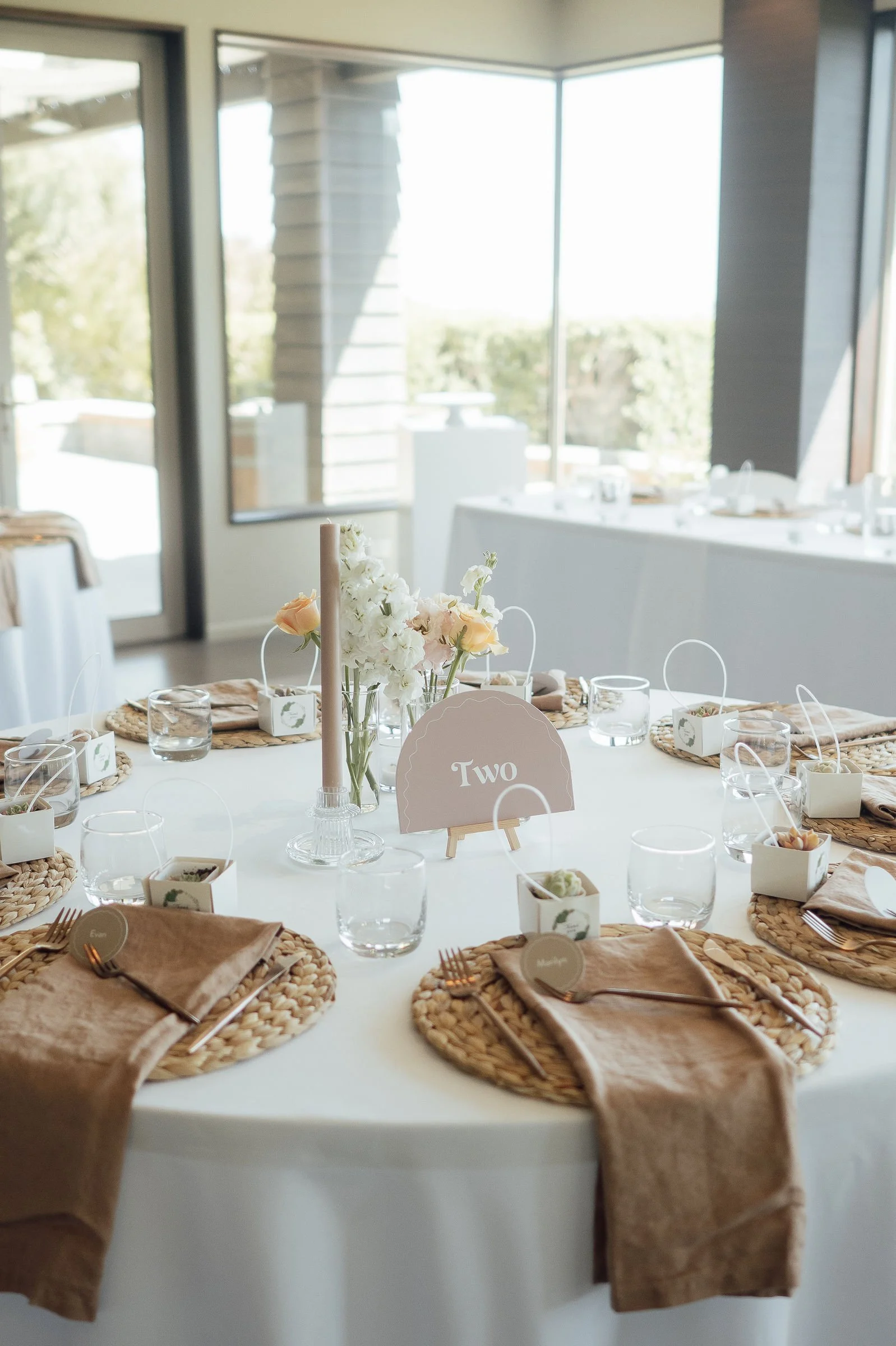 Elegant wedding table setting with name cards and floral centerpieces, ready for guests to enjoy their seating at Waipuna Estate