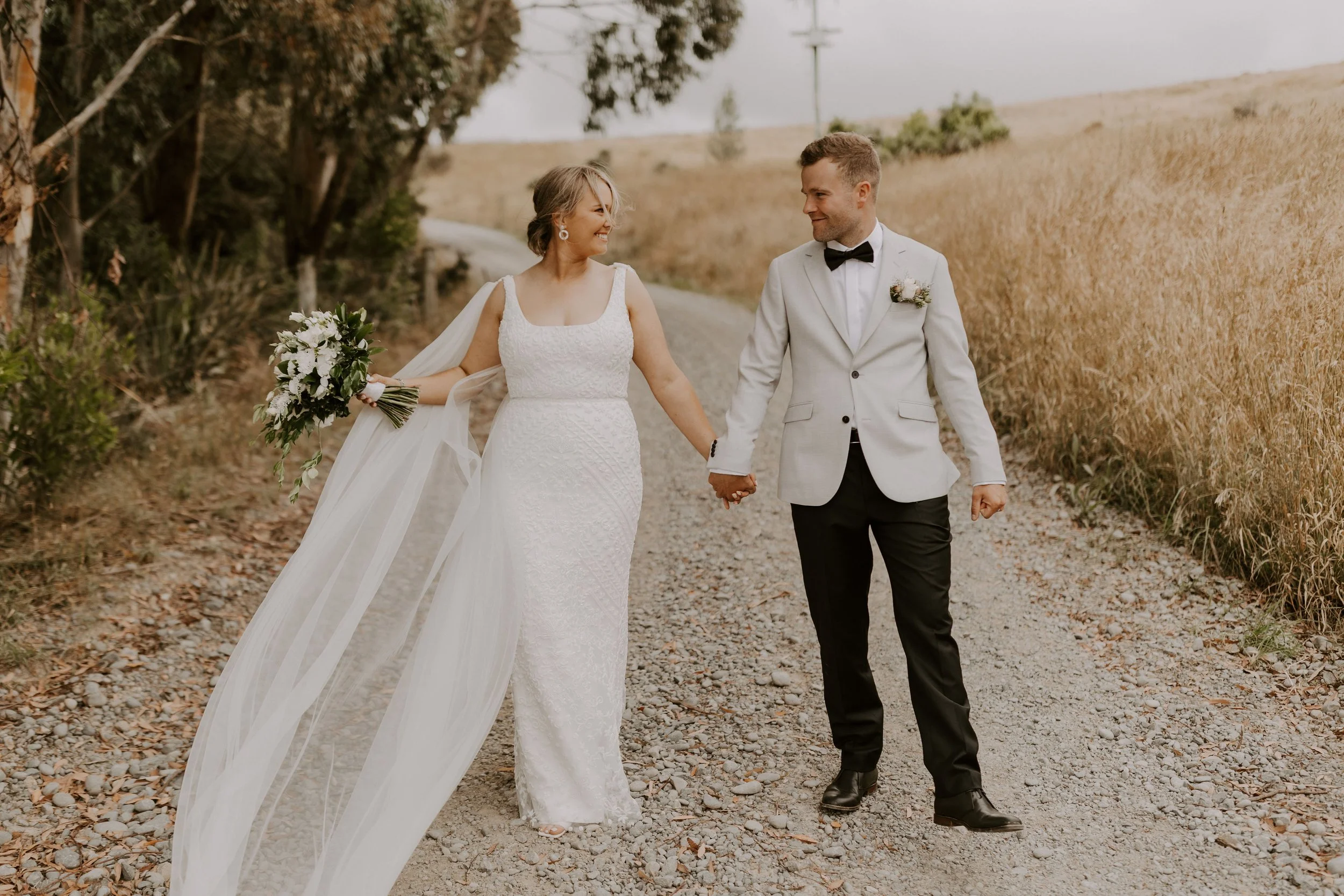 Bride and groom walking together through the scenic grounds at Waipuna Estate