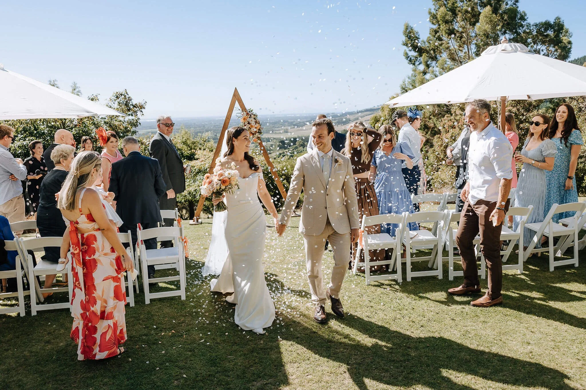 Bride and groom walking back down the aisle with confetti at Waipuna Estate Christchurch