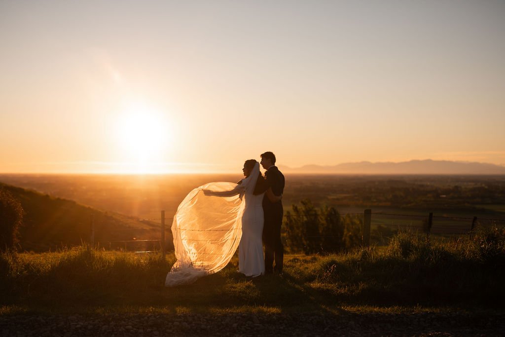 Bride and groom enjoying sunset portraits overlooking Waipuna Estate