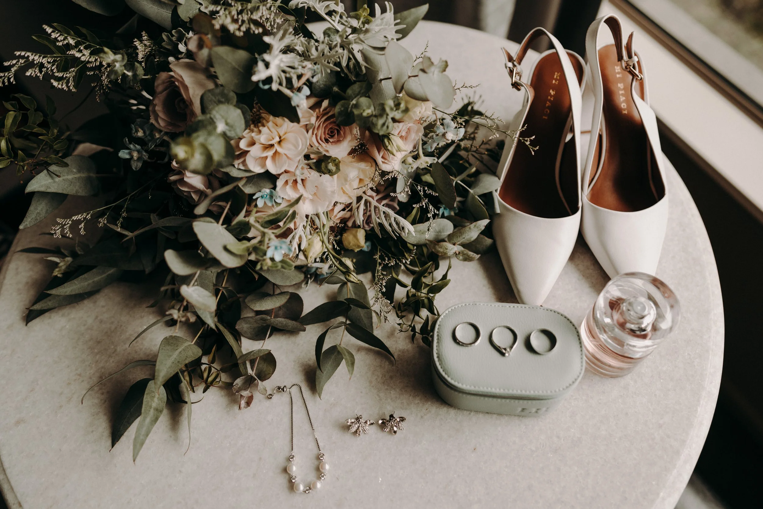 Wedding flatlay with flowers, rings, and styling details representing the early planning stages of a wedding