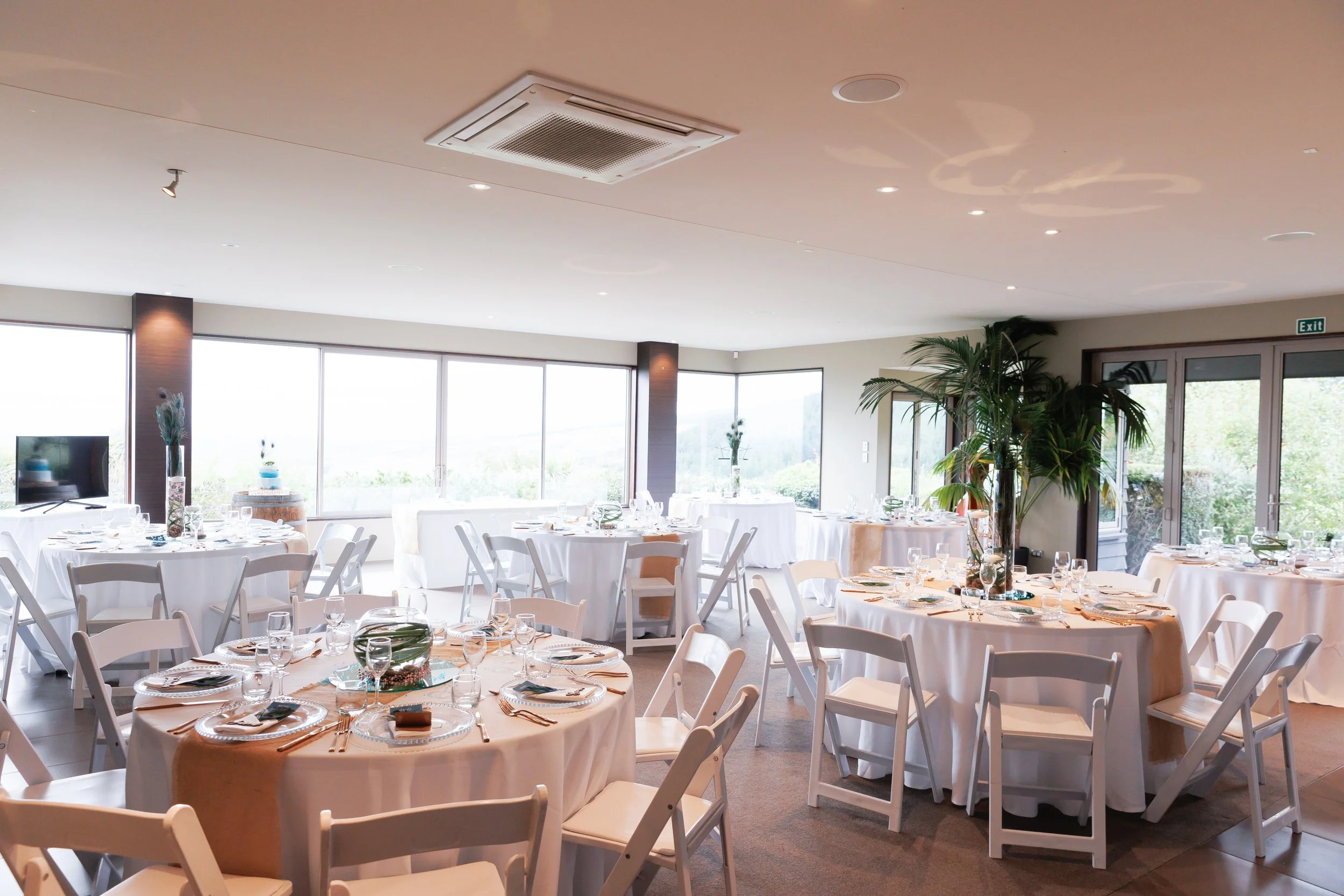 Round wedding tables styled with elegant centrepieces and place settings at Waipuna Estate