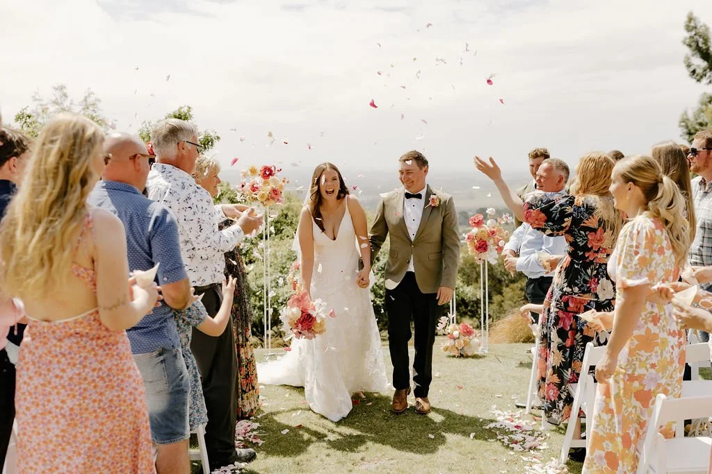 Bride and groom walking out together in their outdoor wedding ceremony at Waipuna Estate