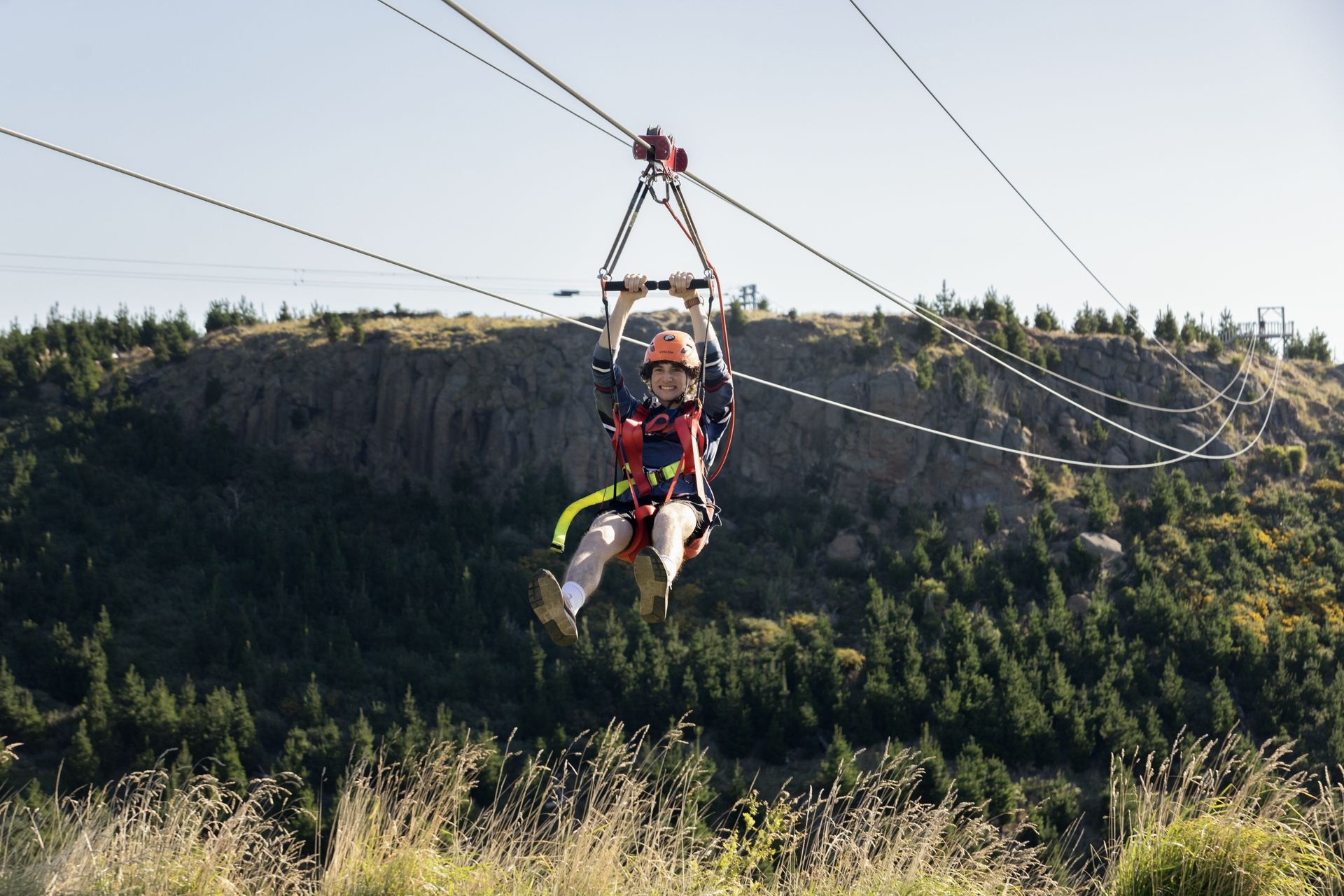Person ziplining over a forested mountain landscape.
