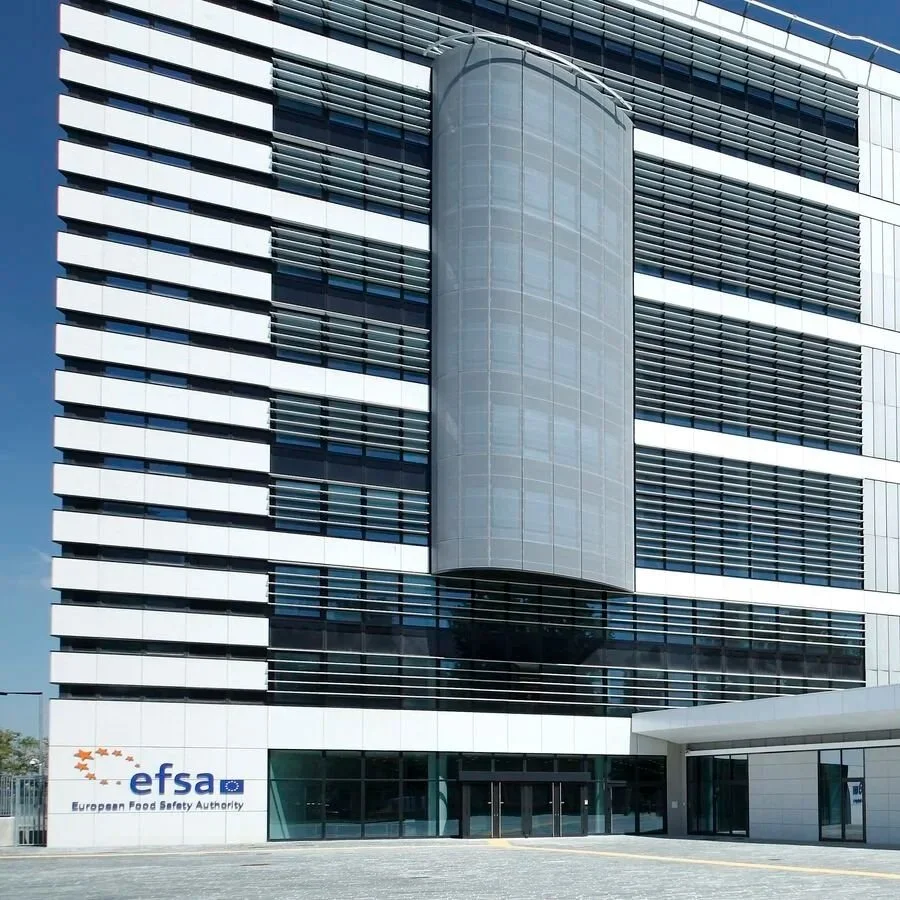 Modern multi-story building with a sign for the European Food Safety Authority (EFSA) at the entrance.