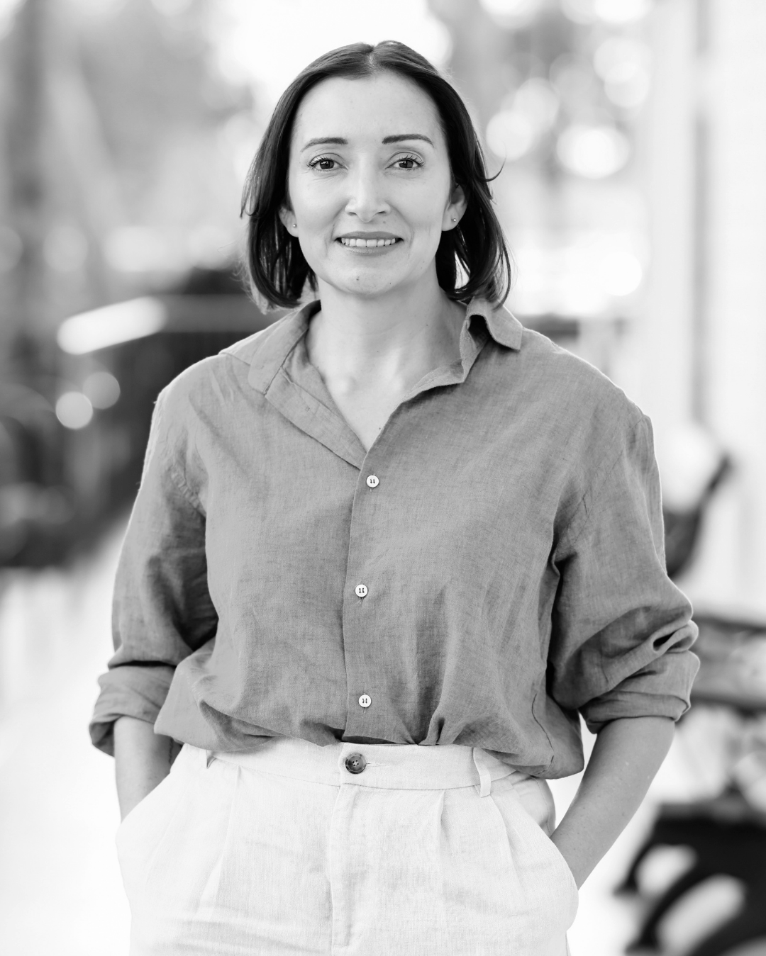 Woman in a blue shirt standing outdoors with a blurred background.