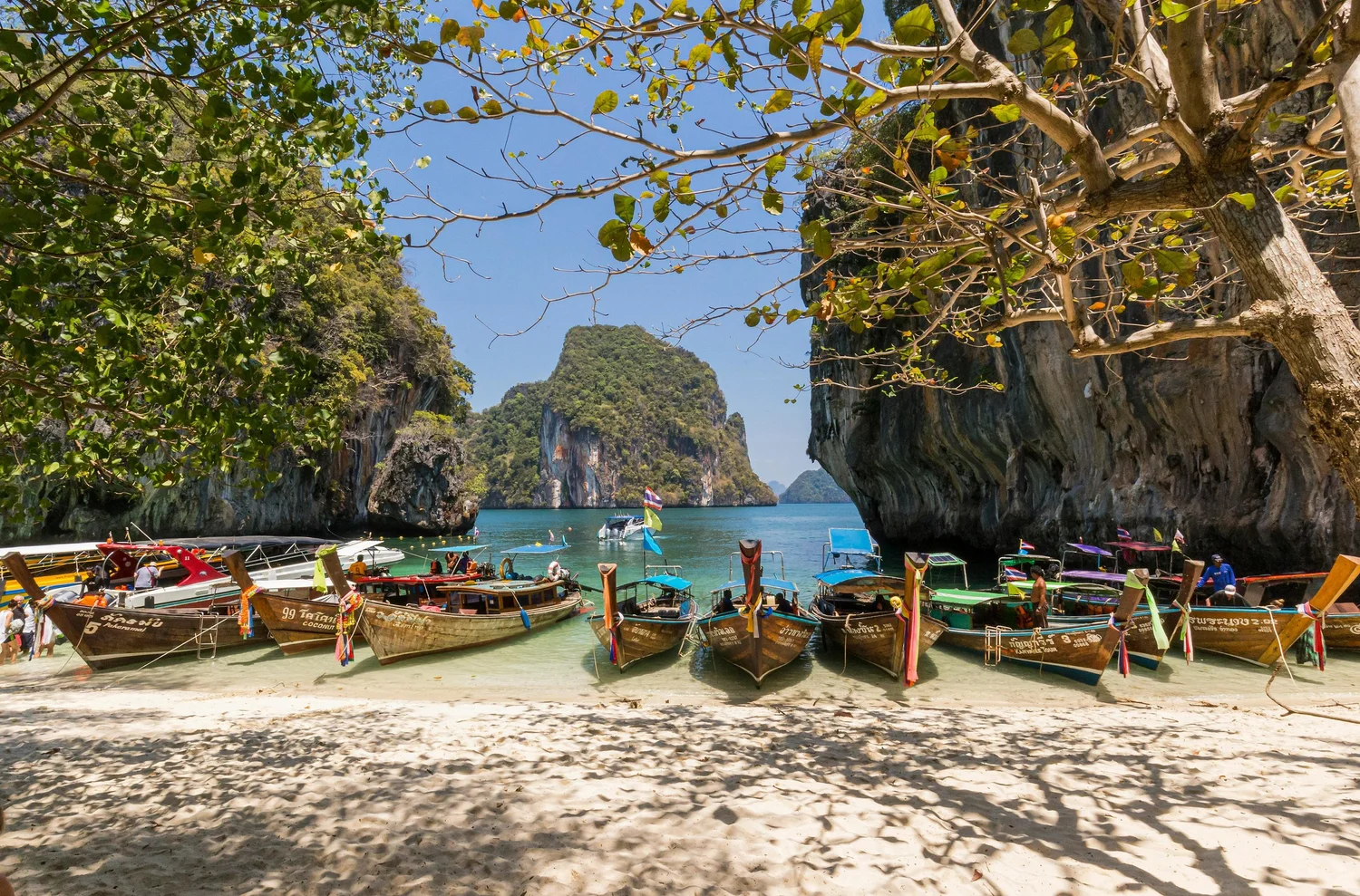 Boats on a tropical beach surrounded by limestone cliffs in Thailand