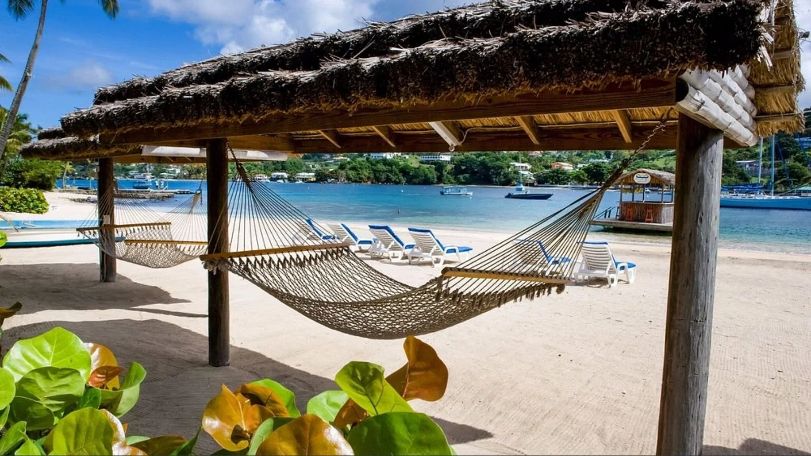 Luxurious hotel swimming pool area with lounge chairs and umbrellas, surrounded by modern buildings and palm trees, during sunset.