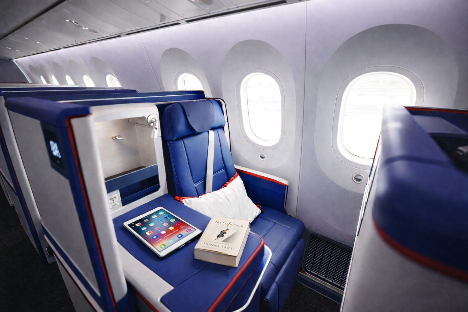 Panoramic view of a luxurious Business Class lie-flat seat with a passenger sleeping soundly under a duvet, in a private pod.