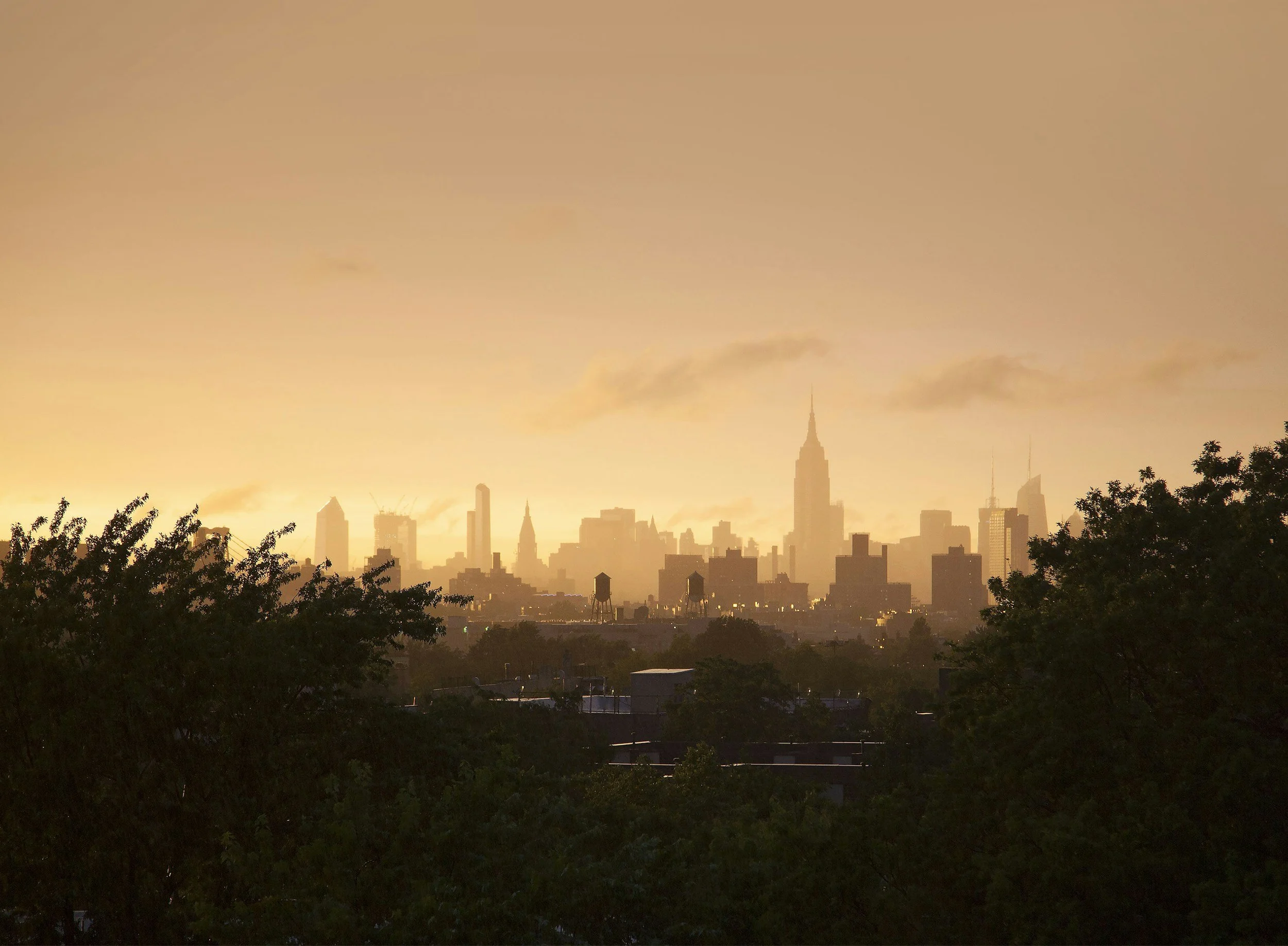 new york skyline in the distance at sunset