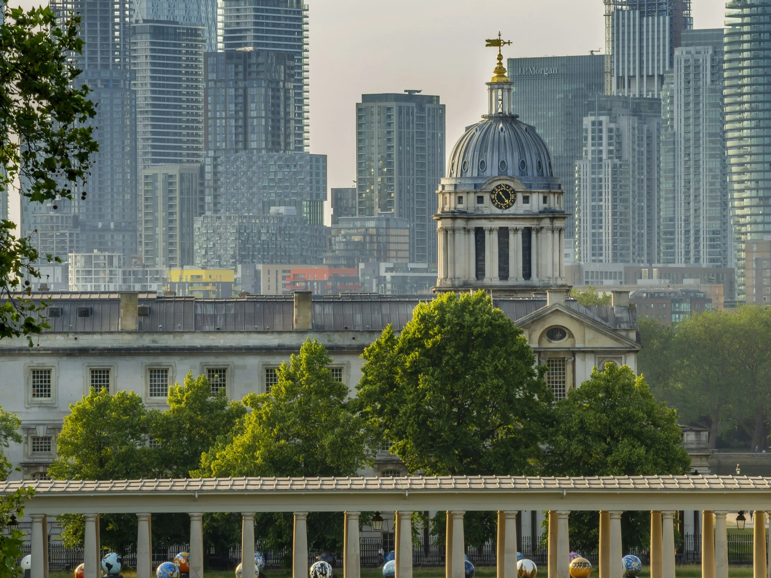 view of old building in greenwich and canary wharf buildings in london behind