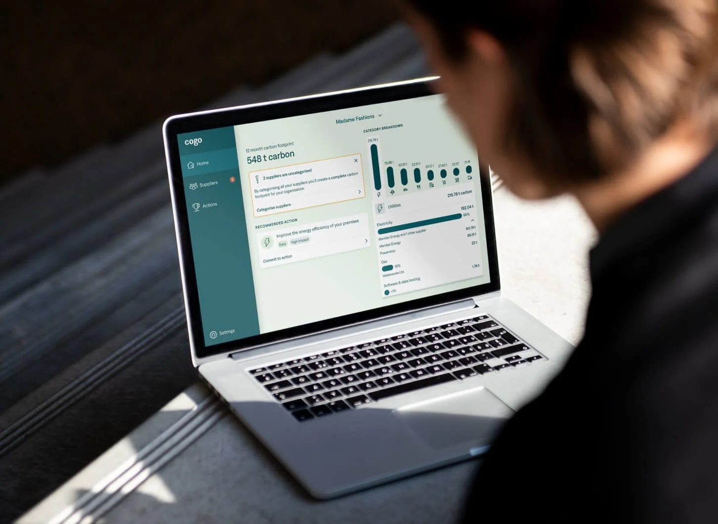 Person looking at a laptop screen displaying data on carbon footprint and energy usage analytics.