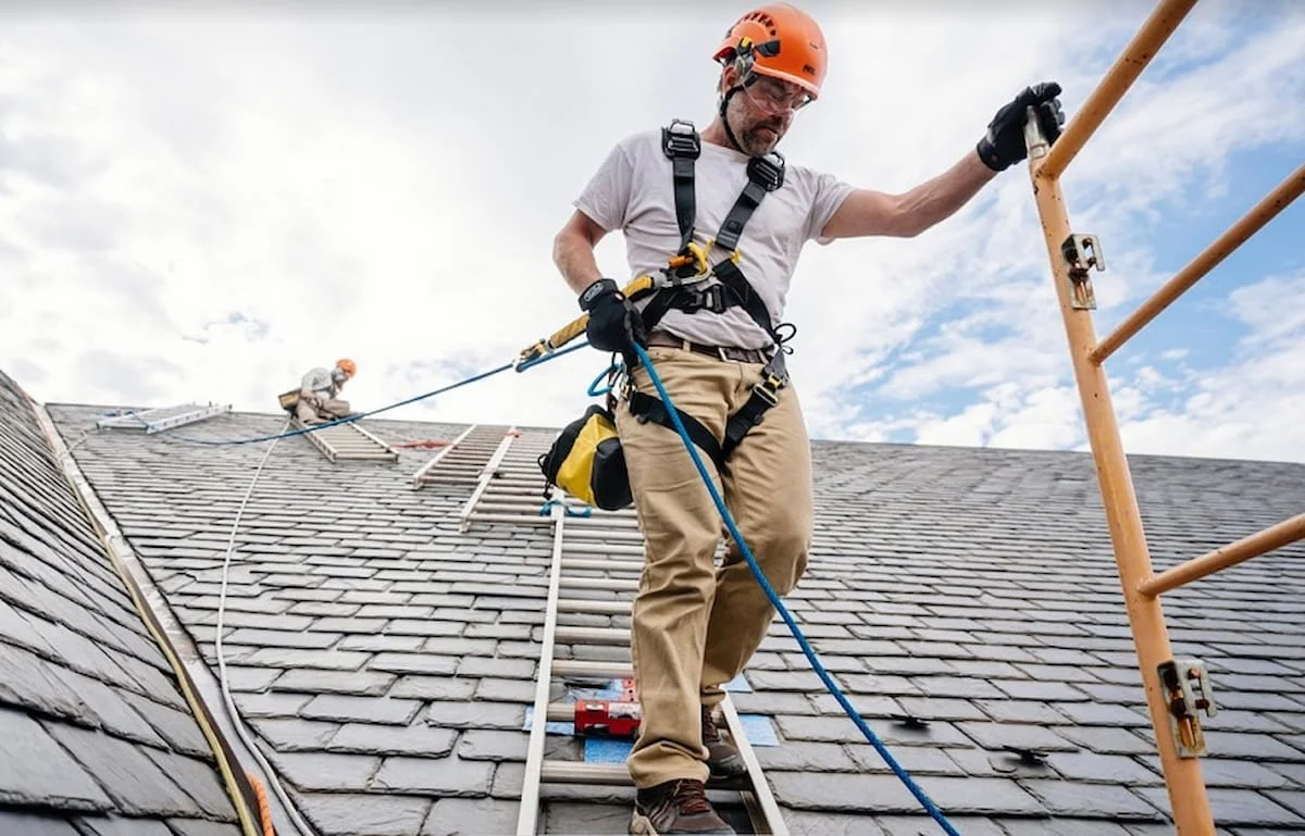 Roofer wearing a safety harness while working on a steep roof.