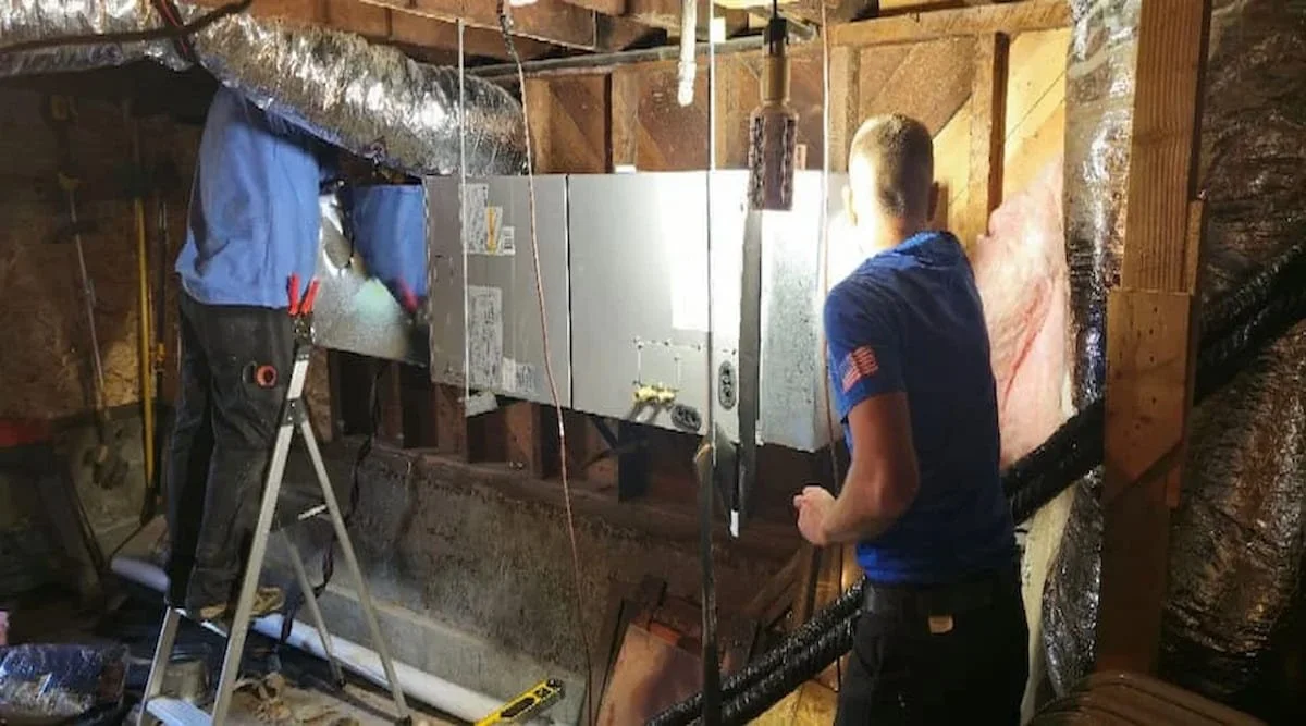 HVAC technicians installing air duct system in attic.