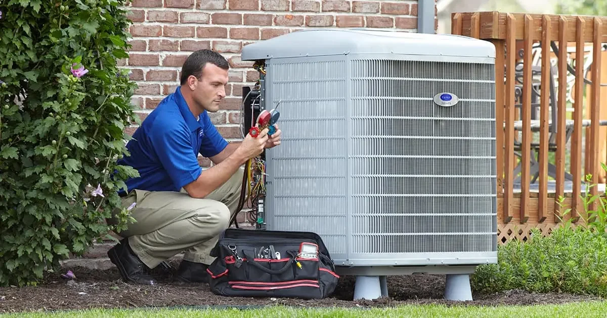 HVAC technician inspecting and repairing an outdoor AC unit.