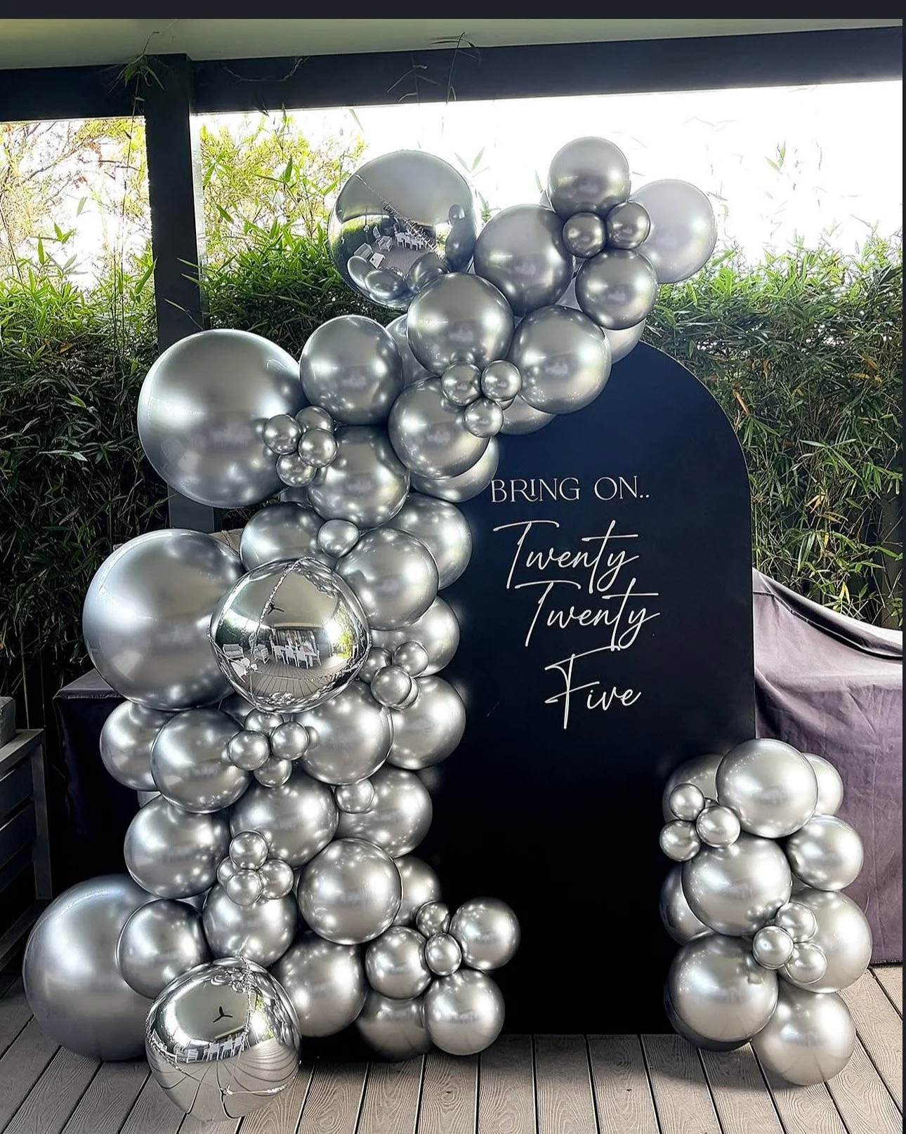 Balloon decoration with silver balloons clustered around a black sign that reads 'Bring on... Twenty Twenty-Five'.