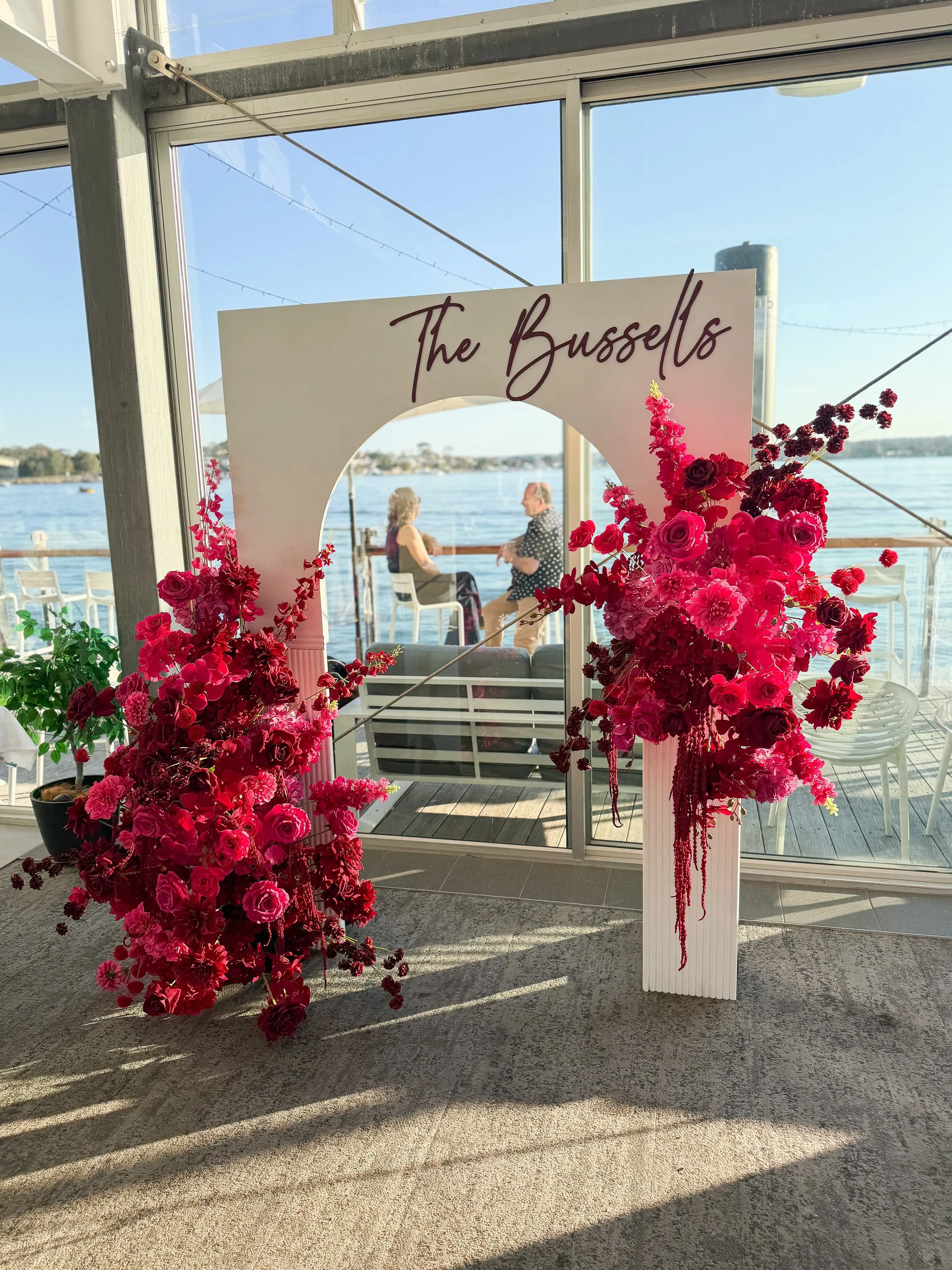 🩷 THE BUSSELLS ❤️

FUCHSIA + DEEP RED&hellip; a combo we&rsquo;ll never get over. ❤️&zwj;🔥

A celebration for the newlyweds, with layers of rich florals framing a custom arched backdrop. All set against the absolutely stunning waterfront views at @