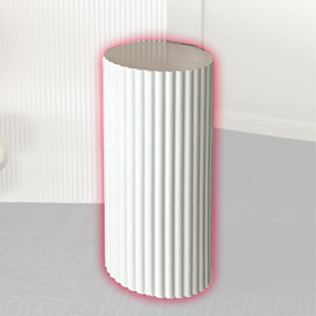 White cylindrical object with vertical ridges standing on a gray carpeted floor in front of a white wall.