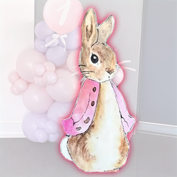 Decorative paper cutout of a bunny wearing a pink jacket, with pastel balloon arrangements in the background.