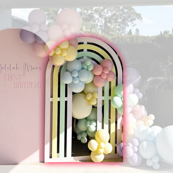 Colorful balloon arch with pastel balloons surrounding a rainbow decoration for a birthday celebration.