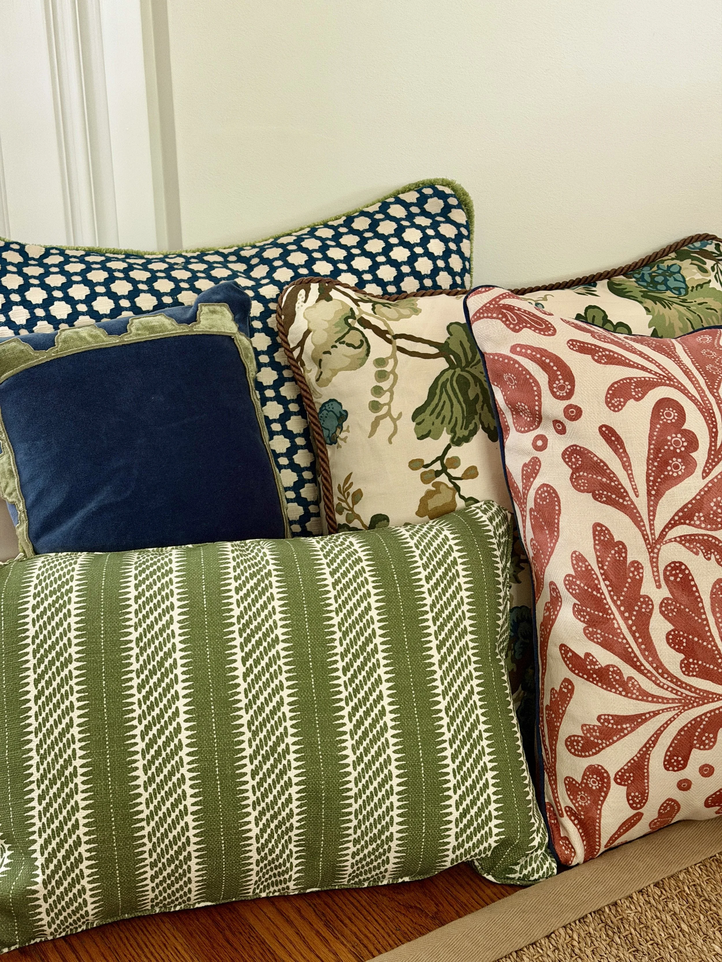 Decorative pillows with multicolored patterns on a striped wooden bench near a light-colored wall.