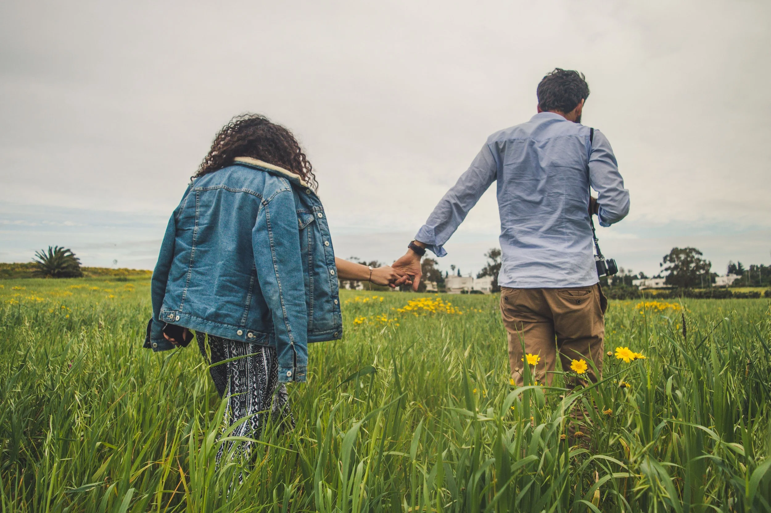 Couple walking hand in hand through a field, representing the renewed connection and hope that affair recovery therapy makes possible