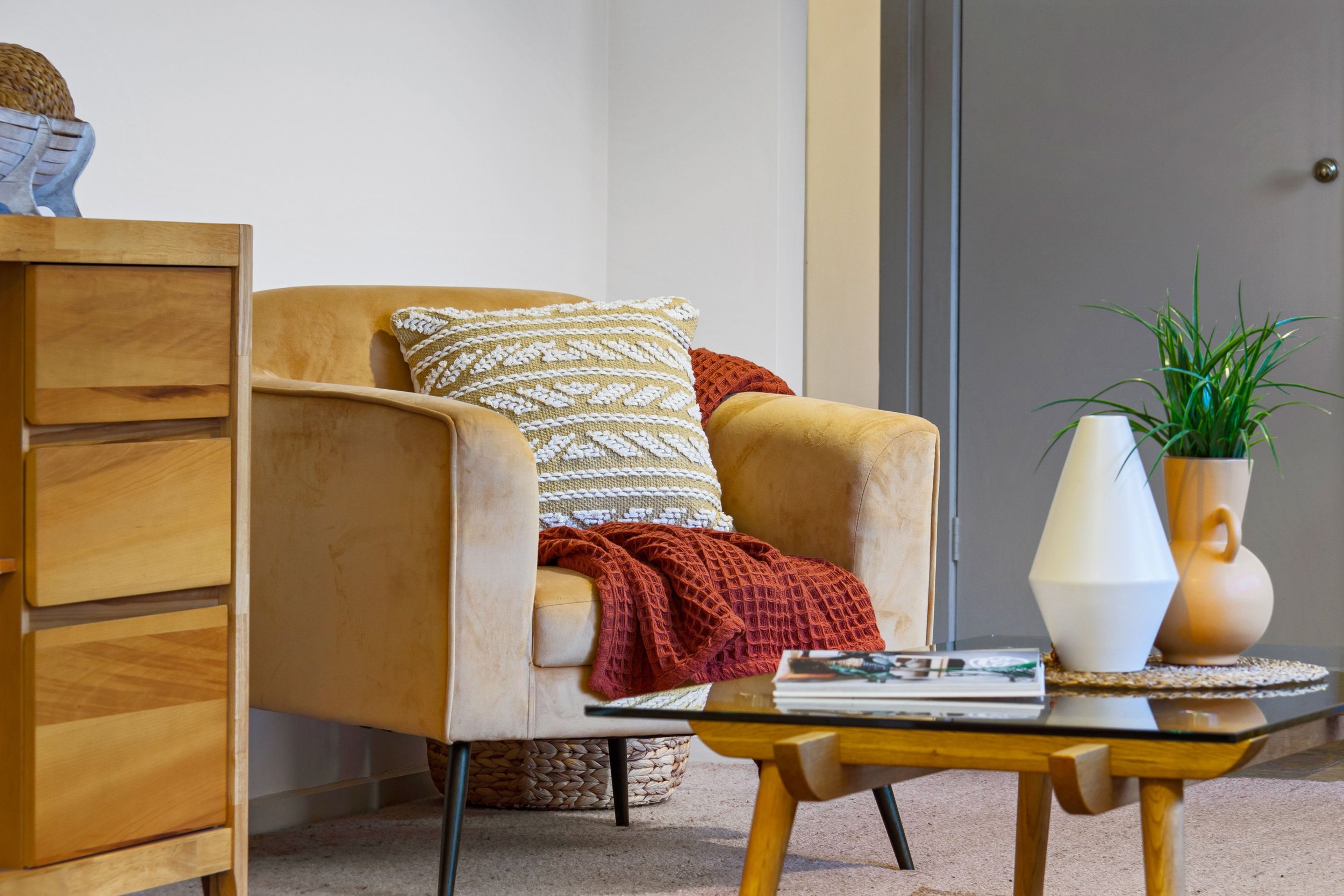A warm modern interior with a comfortable armchair, decorative pillow, and indoor plants, evoking the safe and welcoming space of individual trauma therapy at Seek the Sun Psychotherapy