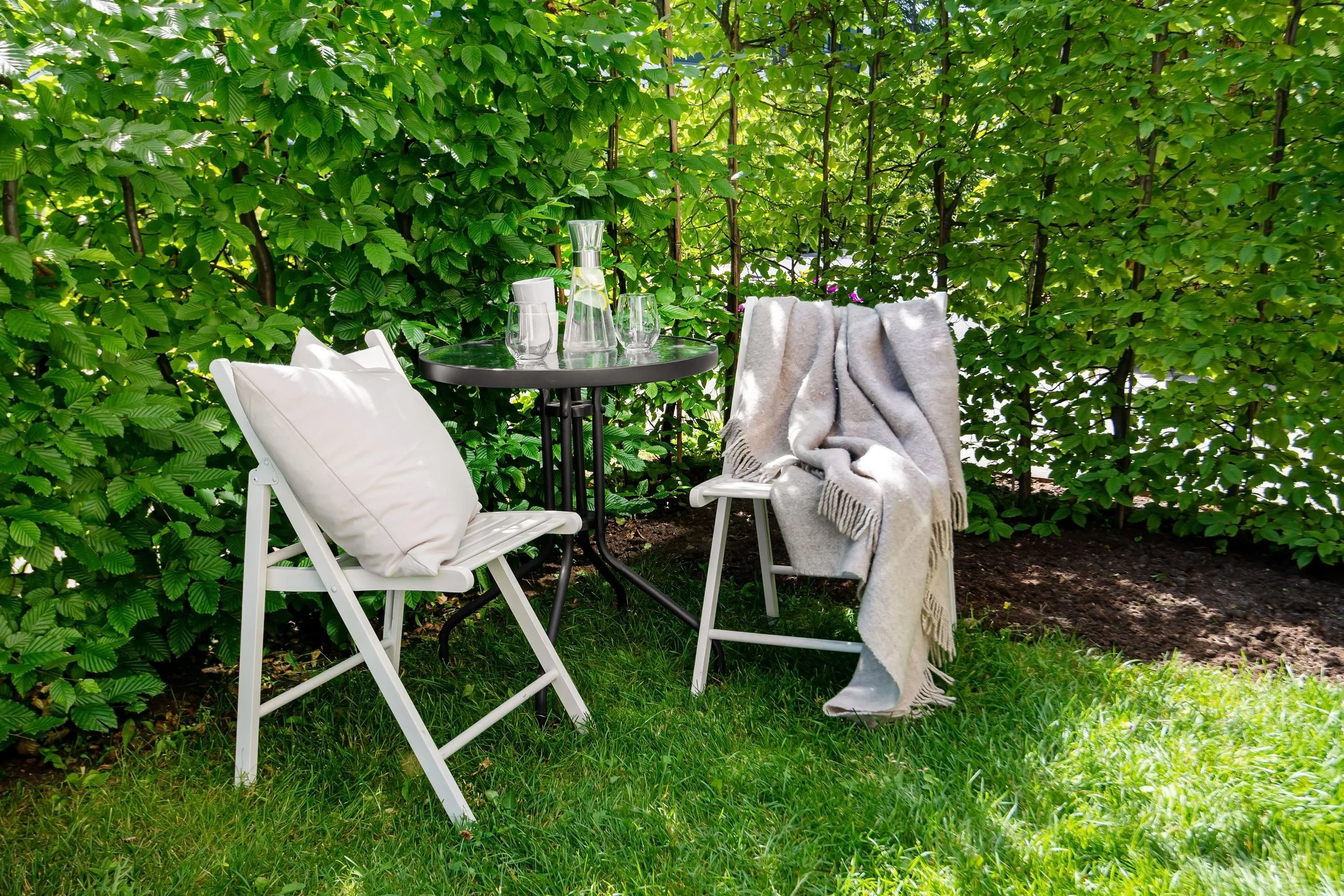 A relaxing outdoor patio with two chairs and a green garden backdrop, evoking the safe and welcoming space of therapy for adult children of emotionally immature parents
